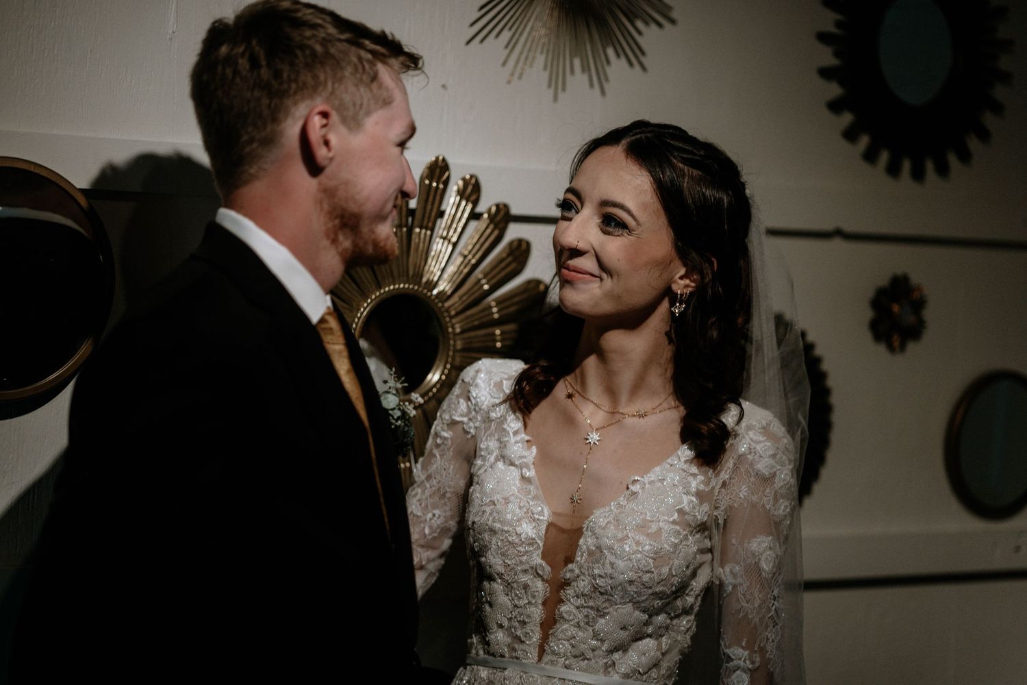 Bride in lace gown and groom in suit share an intimate moment at their wedding reception.