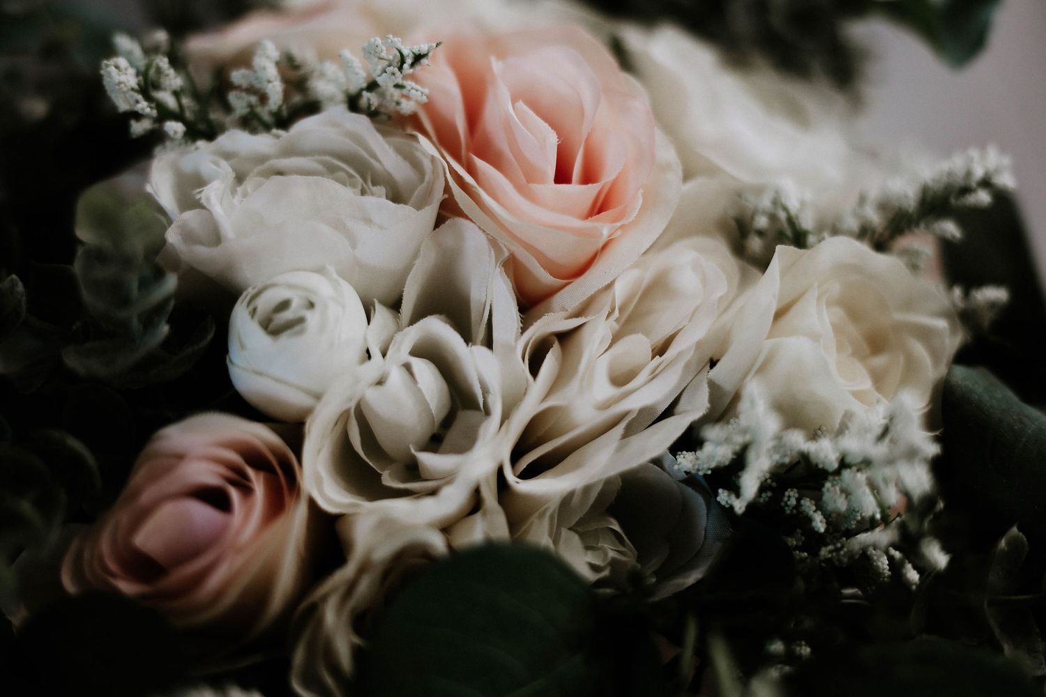 Close-up of a bridal bouquet featuring soft pink and cream roses with lush greenery.