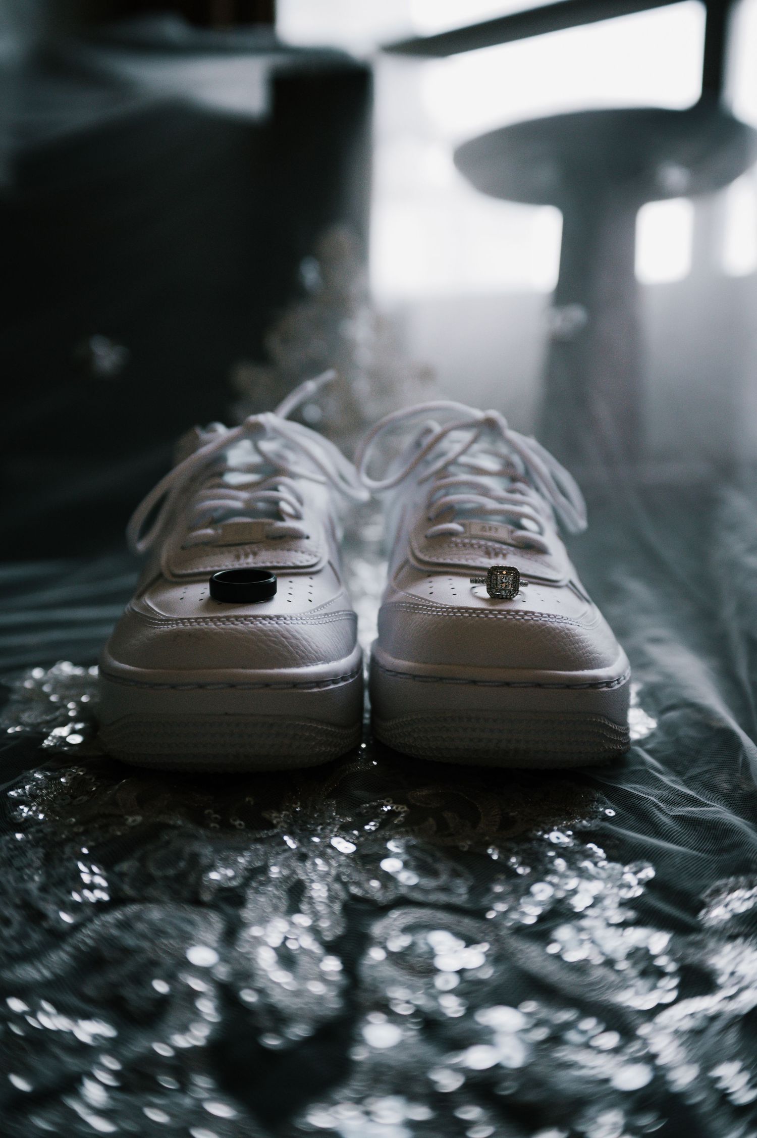 White Nike Air Force 1 sneakers on reflective surface with soft bokeh background.