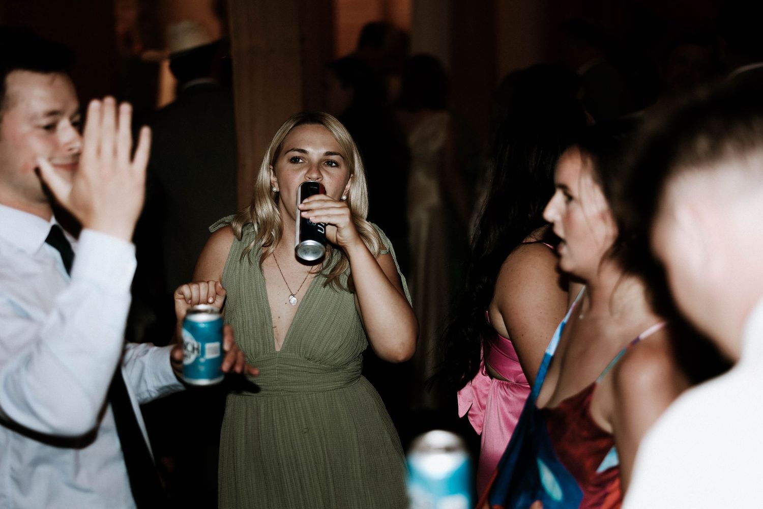Guests dancing and drinking at a wedding reception party in elegant evening attire.