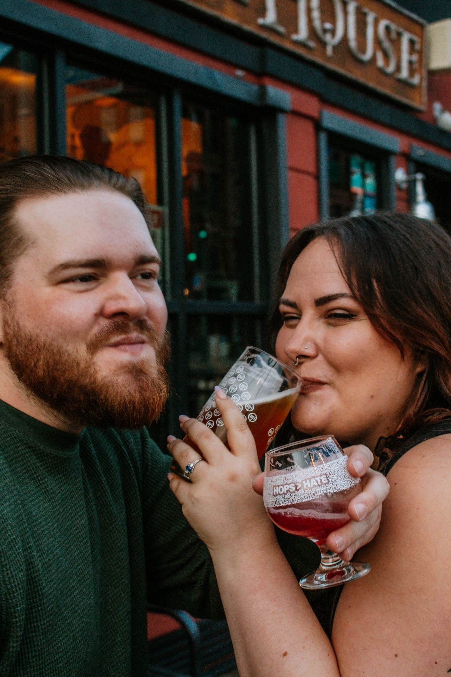 Couple sharing craft beers outside a brewhouse in West Third Street Historic District in Dayton, Ohio, smiling and enjoying drinks together.