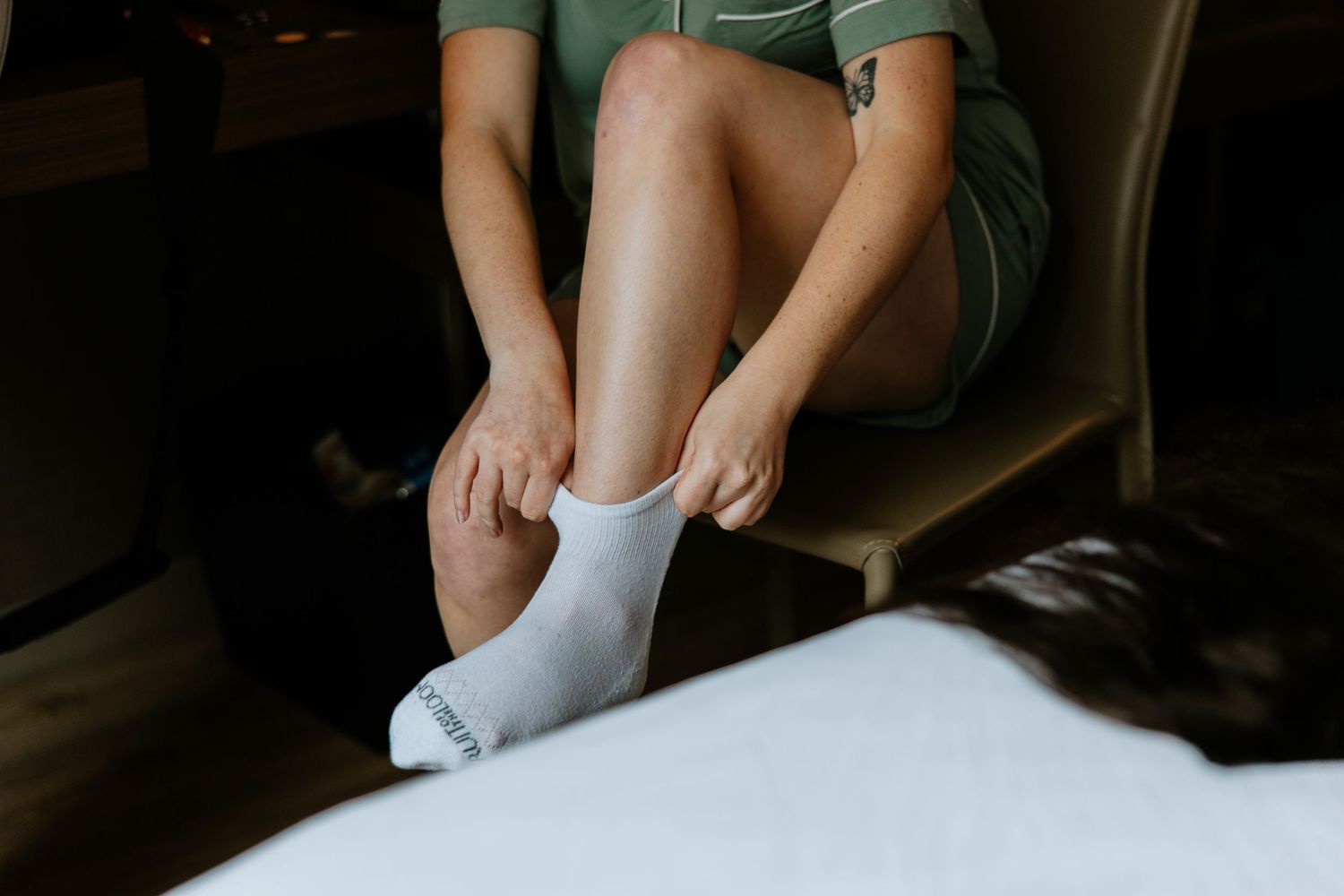 Close-up of bridesmaid pulling on white socks while getting ready for wedding.