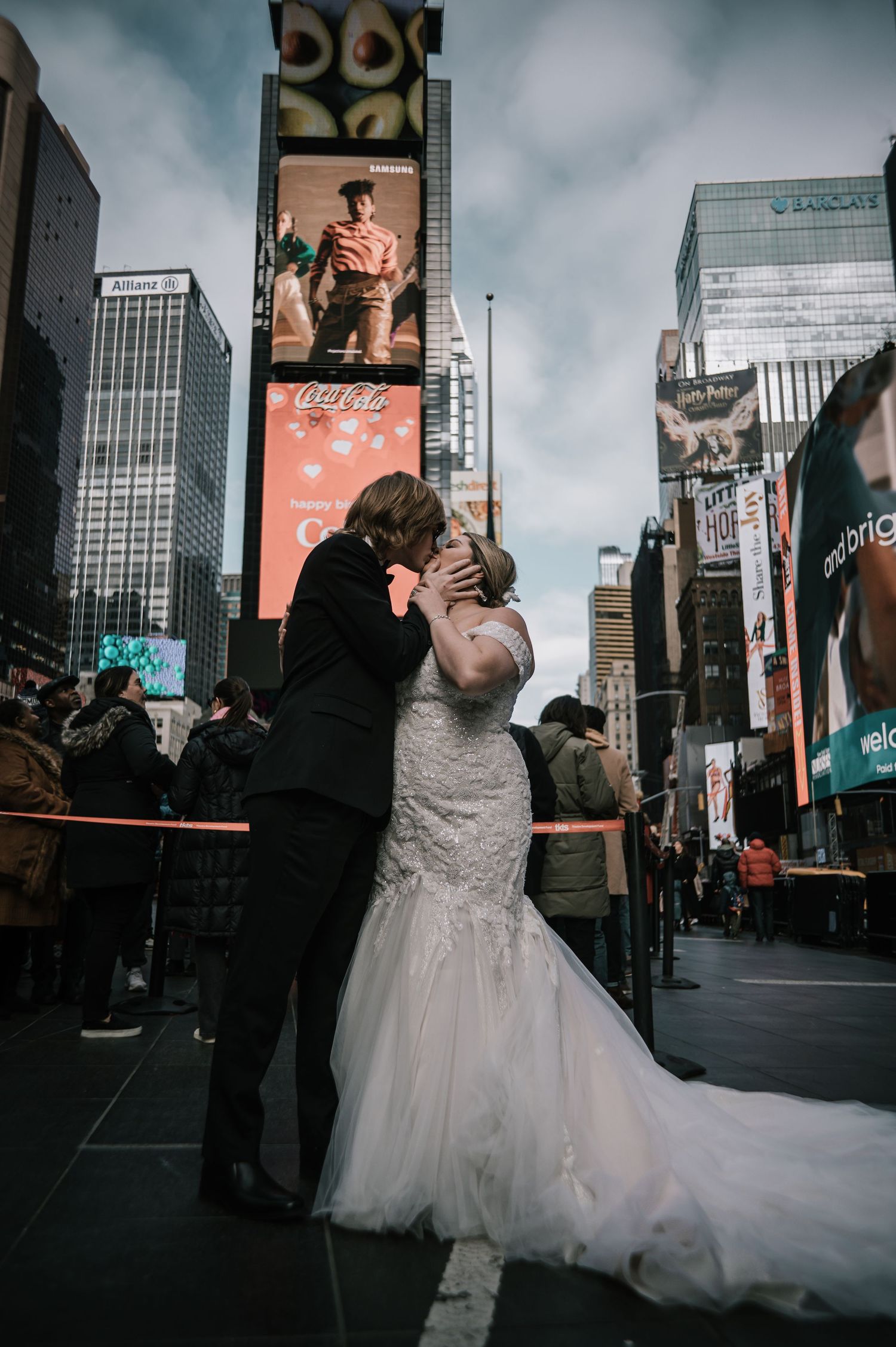 Wedding couple kissing in Times Square NYC, bride in fitted white lace gown with flowing train.