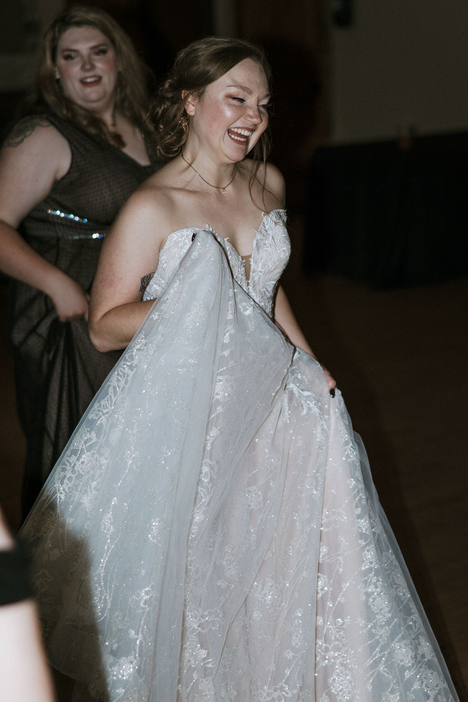 Laughing bride in a lace ball gown lifting her dress while dancing at her wedding reception at Urban Artifact in Cincinnati, Ohio