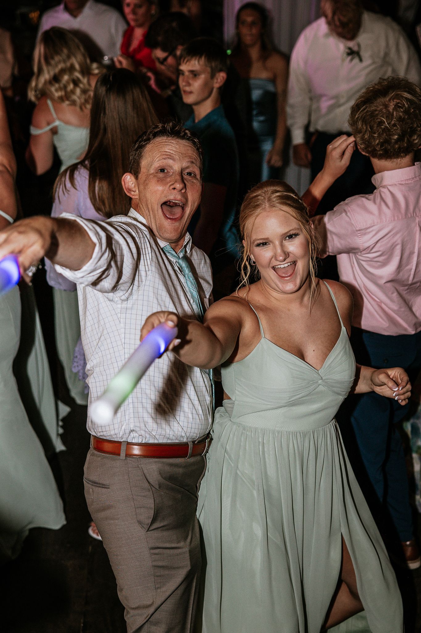Guests dancing joyfully at a wedding reception, holding glow sticks, dressed in formal attire at The Brightside in Dayton, Ohio