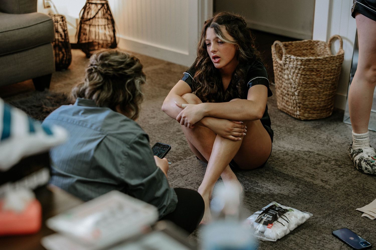 Two women sitting on a carpeted floor having an intimate conversation in a cozy living room.