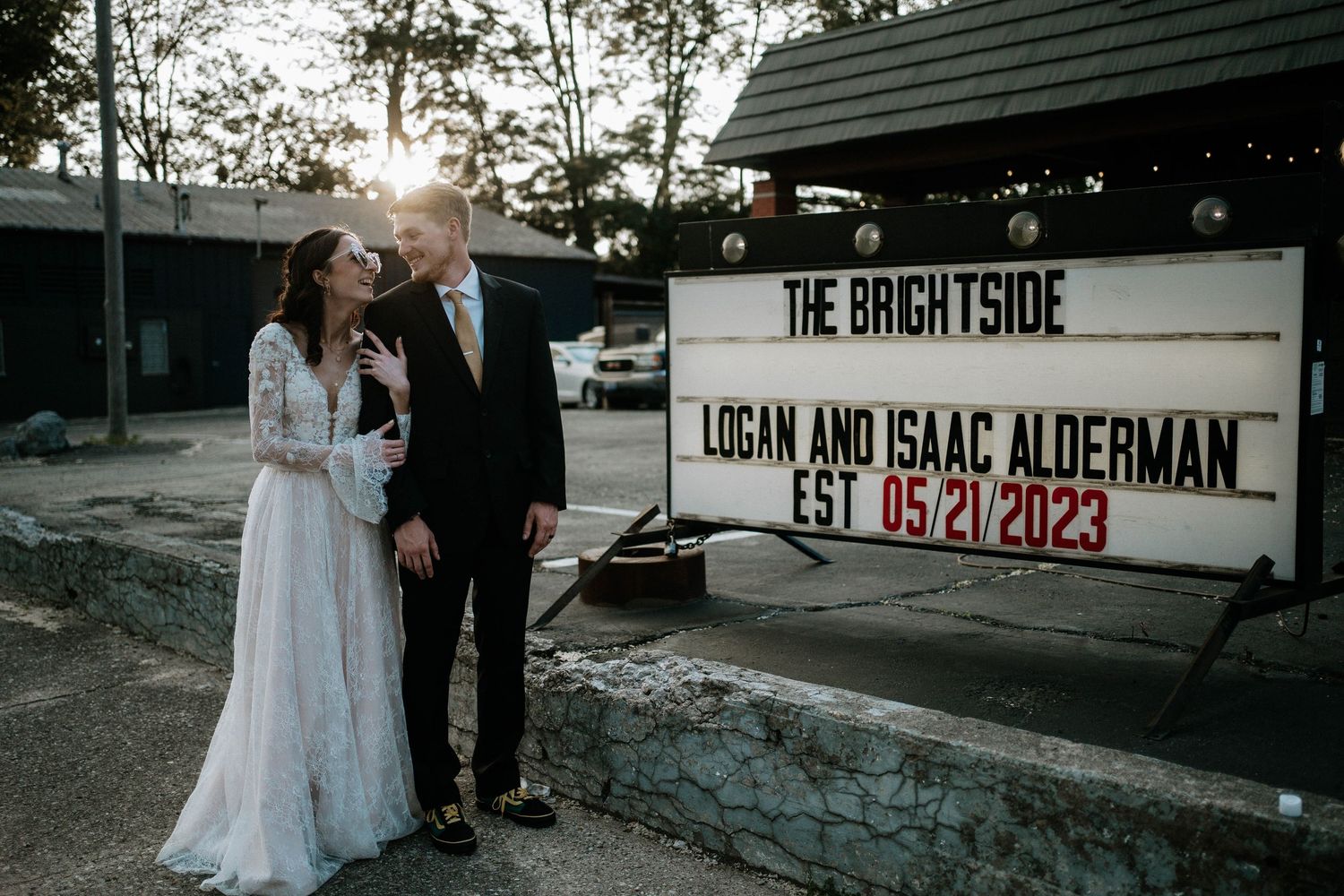 Bride and groom pose before The Brightside wedding venue sign celebrating Logan and Isaac Alderman, est. 05/21/2023.