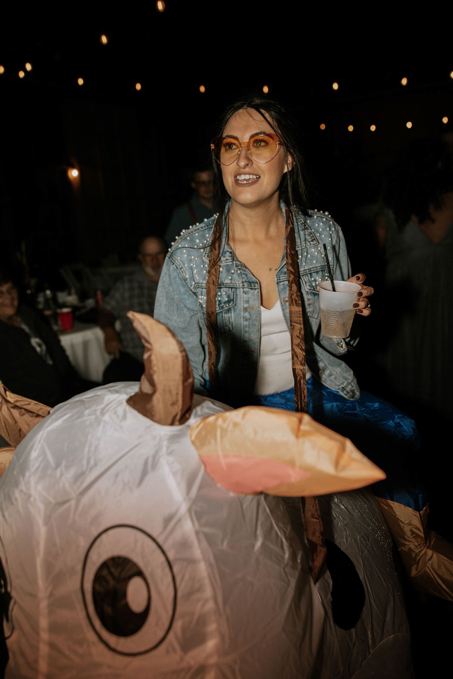Woman in denim jacket rides an inflatable unicorn costume at an outdoor evening wedding reception at The Brightside in Dayton, Ohio
