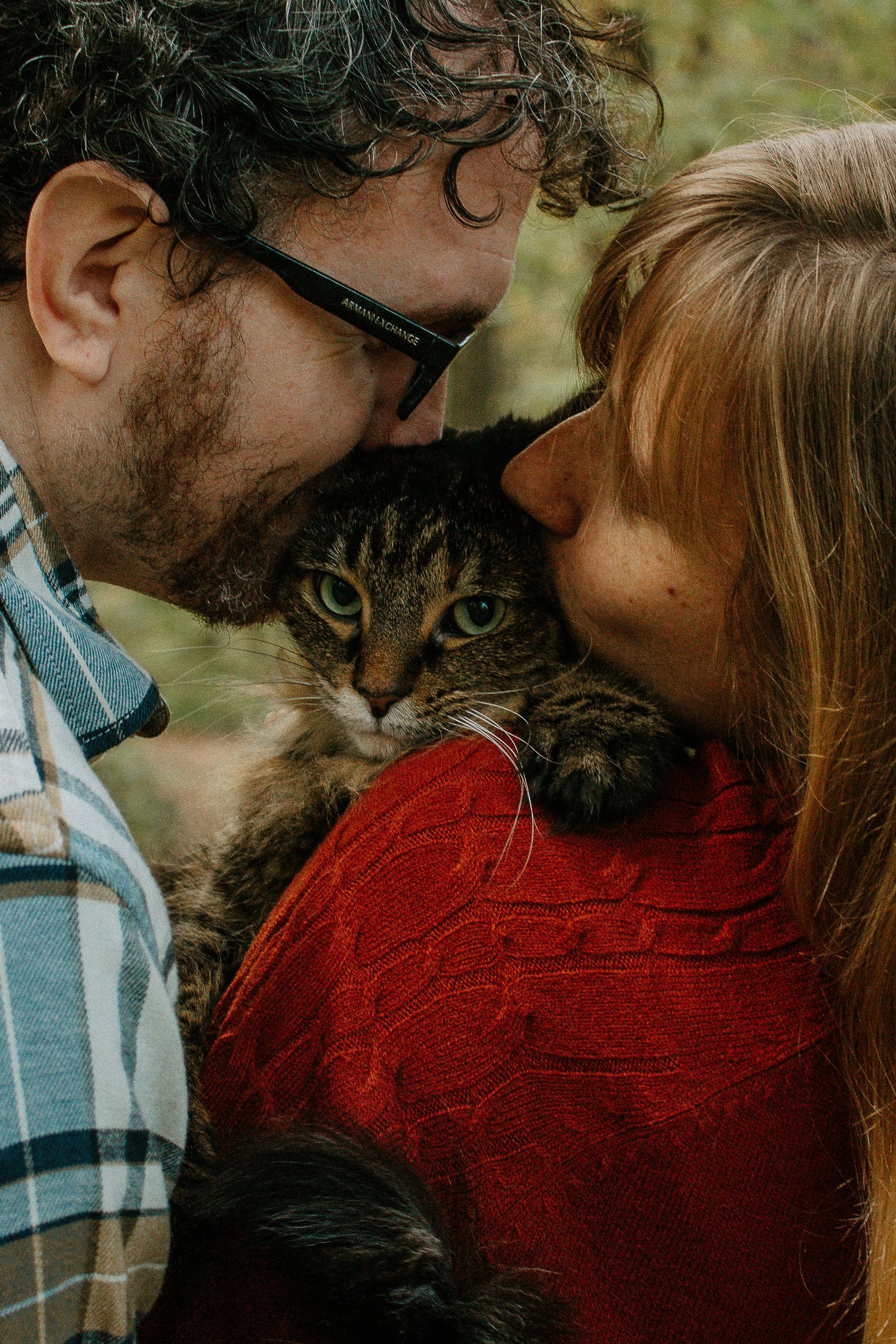 A couple lovingly nuzzles their tabby cat between their faces in an affectionate outdoor portrait in Cincinnati, Ohio