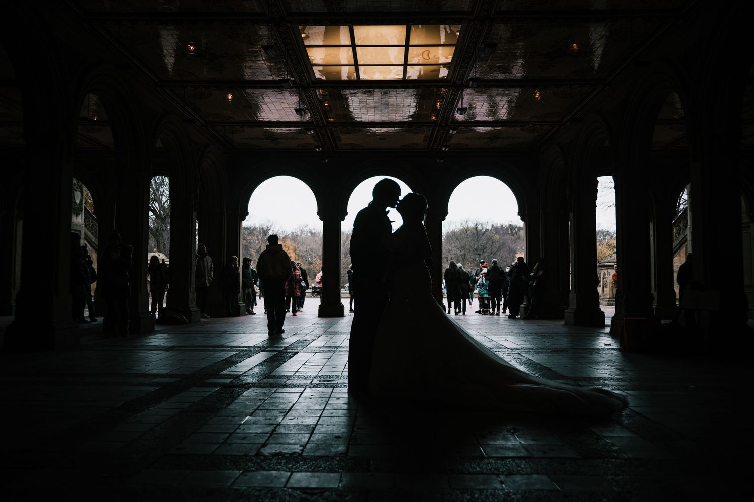 Dramatic silhouette of bride and groom kissing under Bethesda Terrace arches in Central Park.