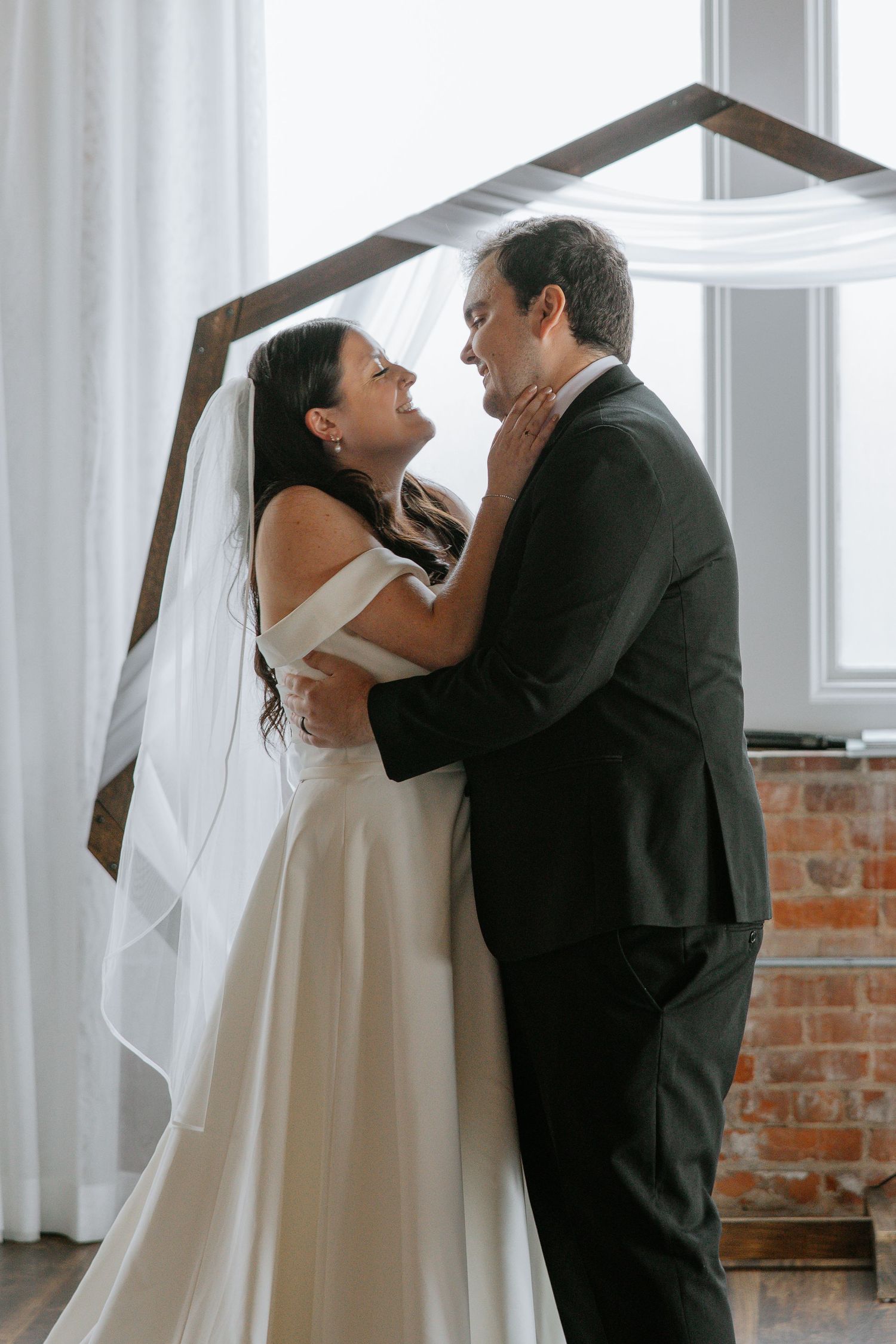 Bride and groom embracing and smiling at each other after wedding ceremony.