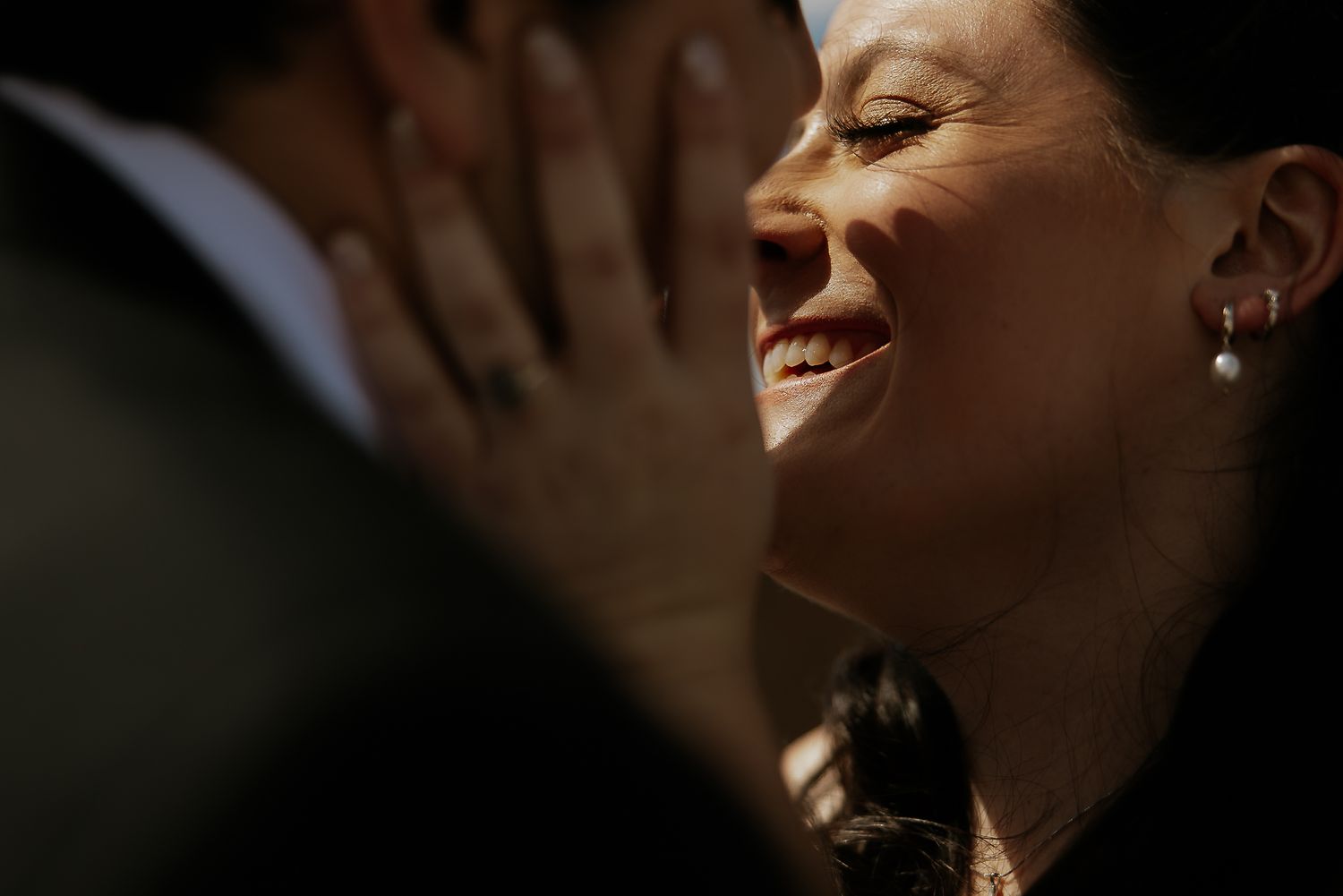 Radiant bride laughs joyfully while facing her groom in a beautifully lit intimate wedding moment.