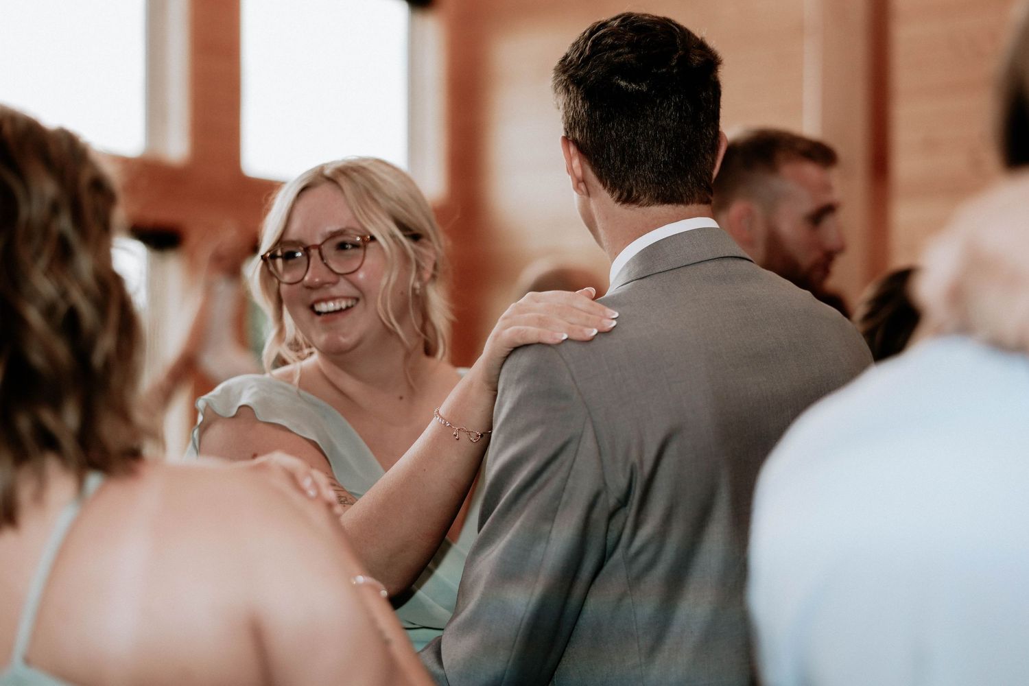Wedding guest smiling and dancing with groom during lively rustic wedding reception.