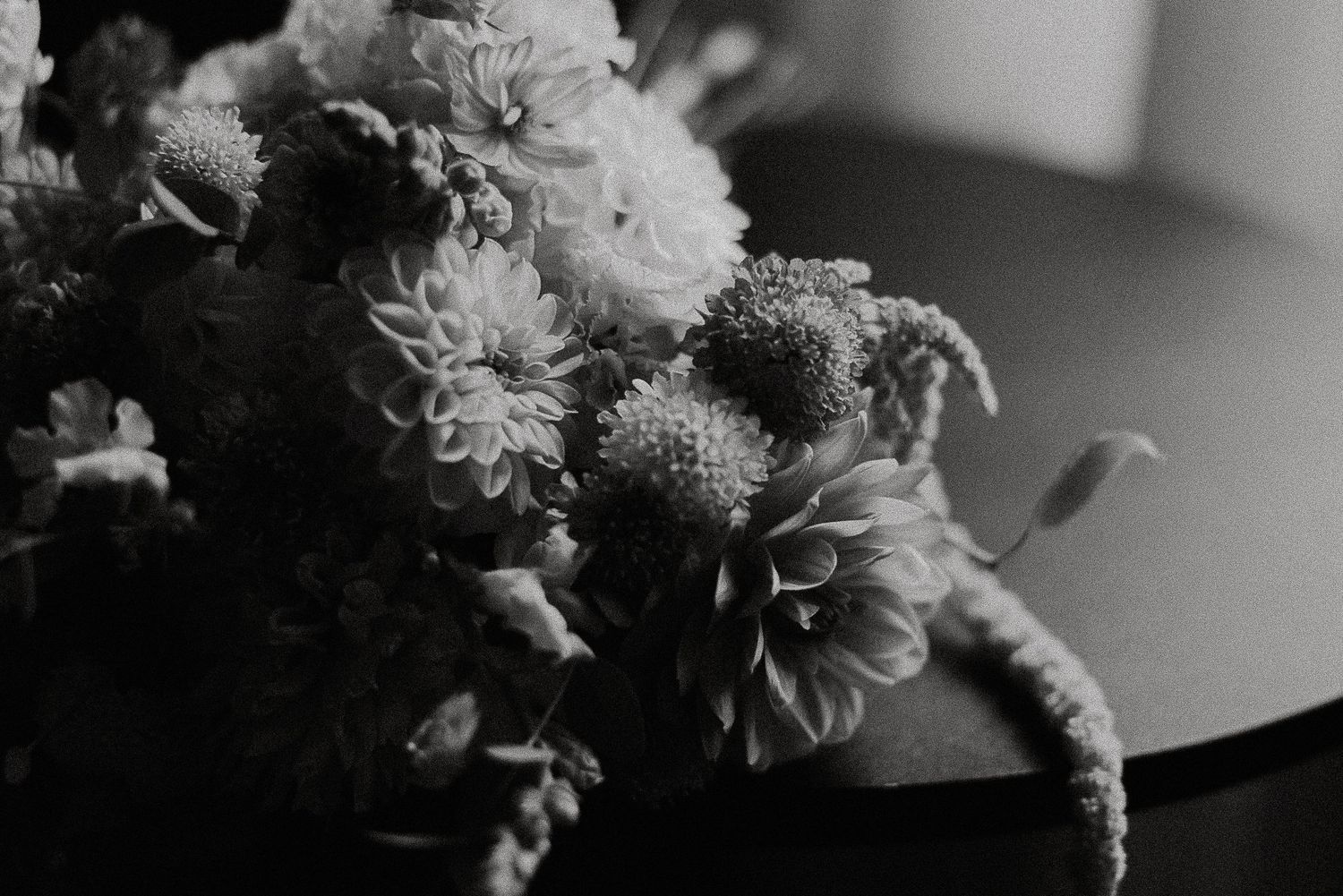 Black and white close-up of textured chrysanthemums and wildflowers in a romantic bridal bouquet arrangement.
