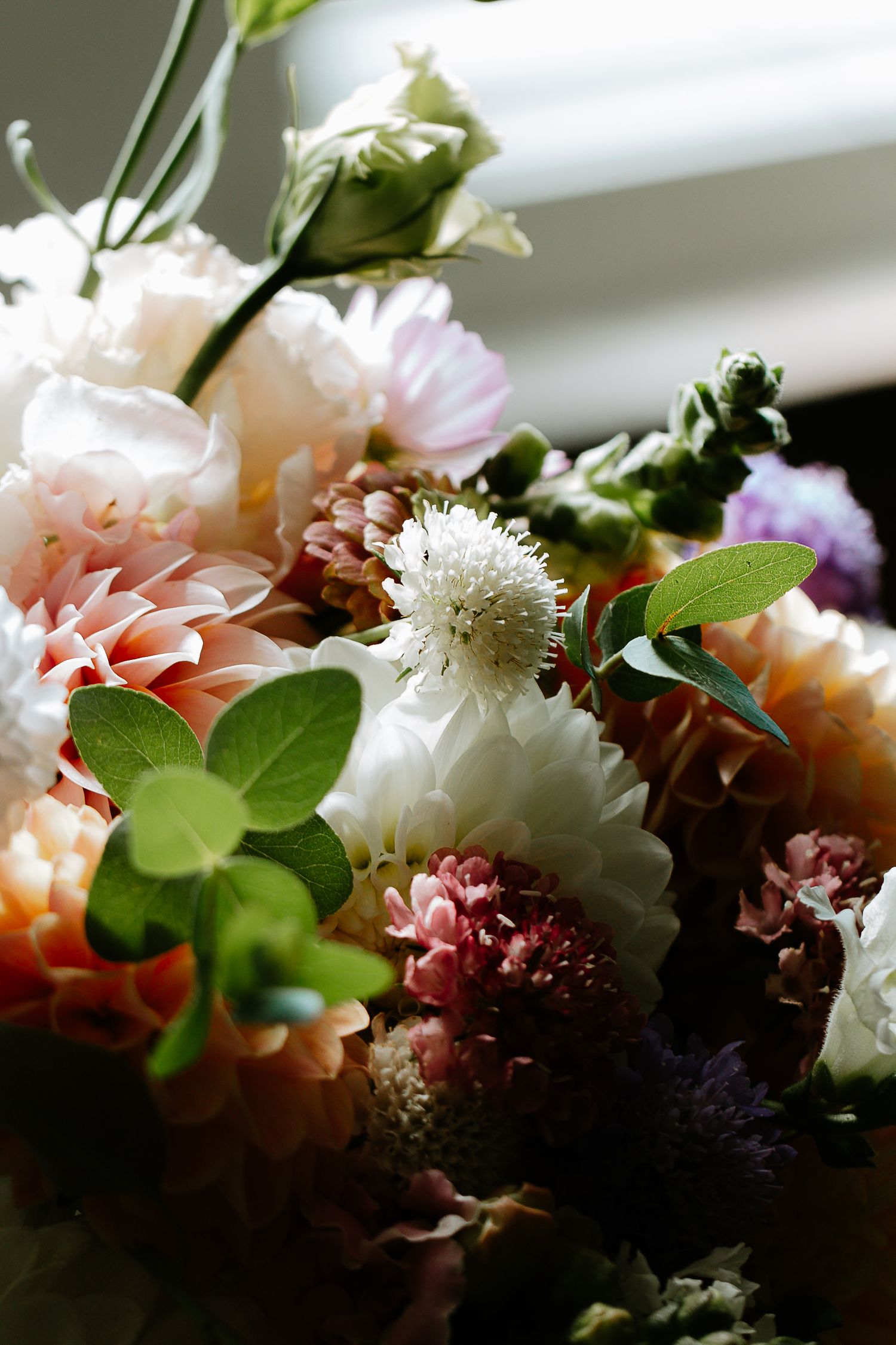 Lush bridal bouquet featuring pink dahlias, white mums, burgundy blooms, and green foliage.