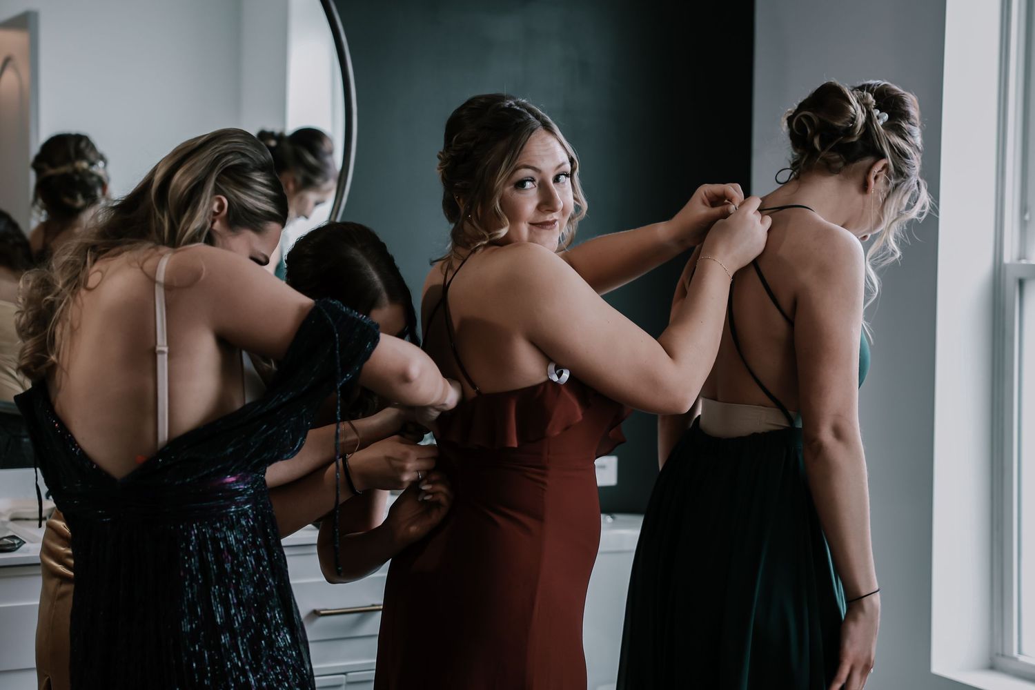 Bridesmaids in elegant dresses helping each other get ready before a wedding ceremony at The Vue in Columbus, Ohio