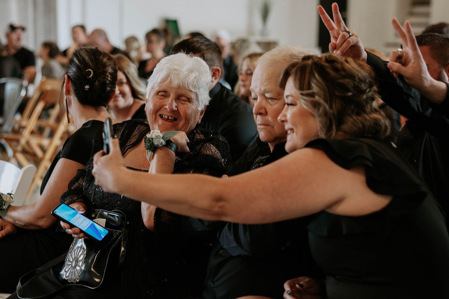 Group of guests in black attire taking a fun selfie together at a wedding reception celebration.