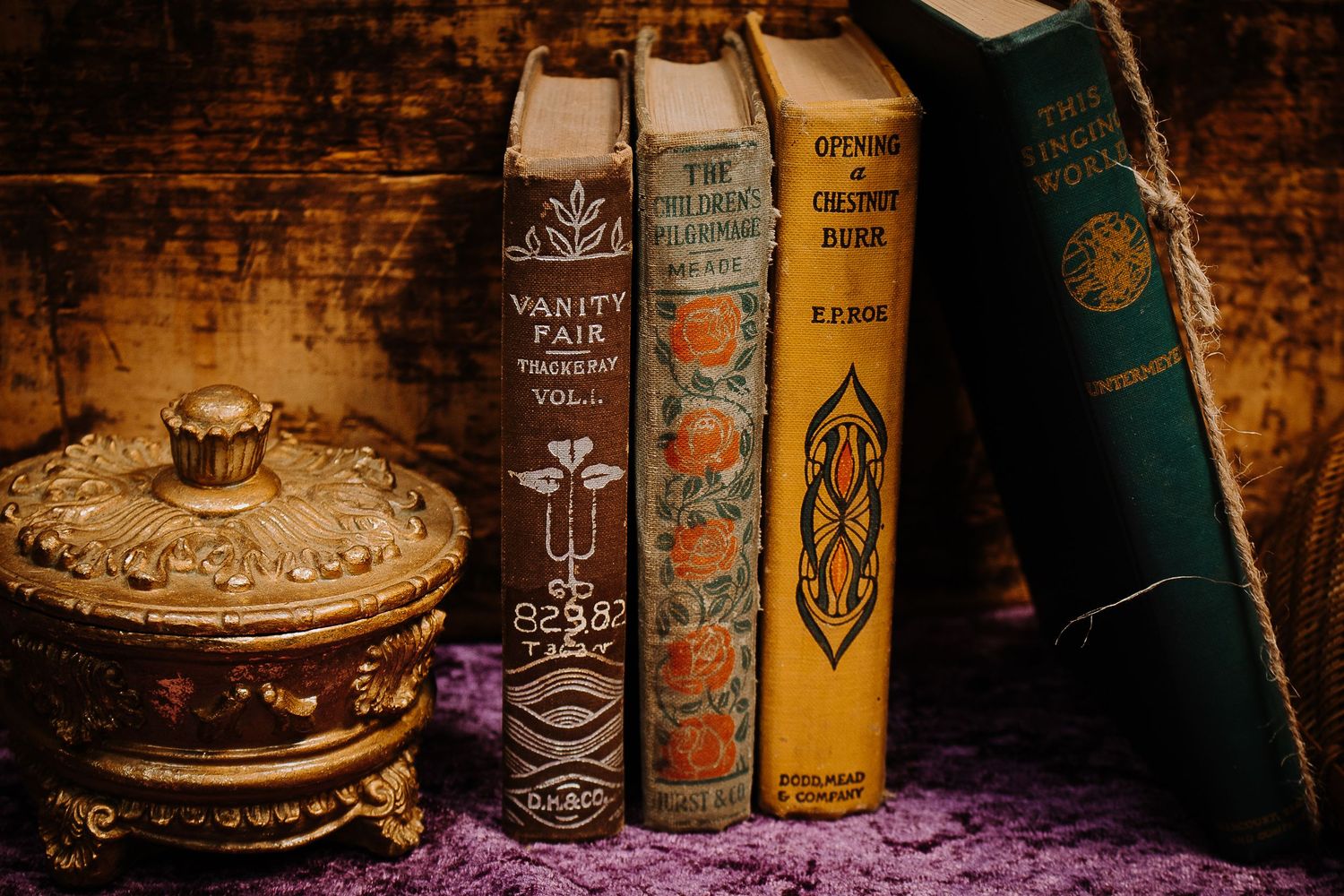 Antique books including Vanity Fair displayed on a shelf beside an ornate golden decorative box.