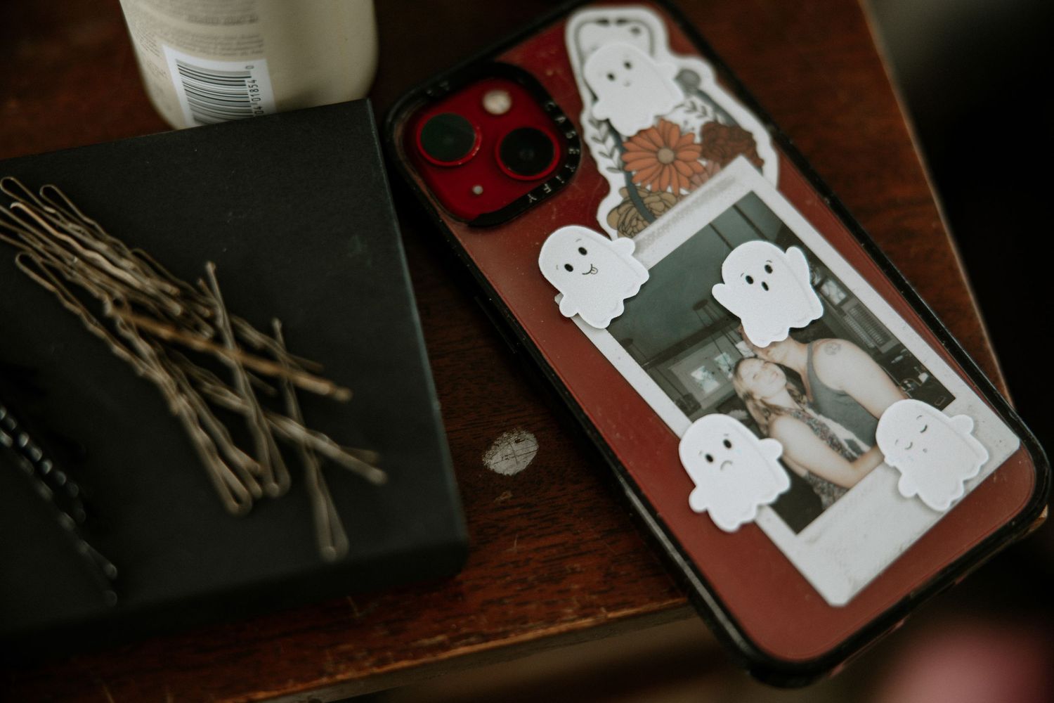 Red phone case with ghost stickers and a wedding photo next to bobby pins on a wooden table at Urban Artifact in Cincinnati, Ohio