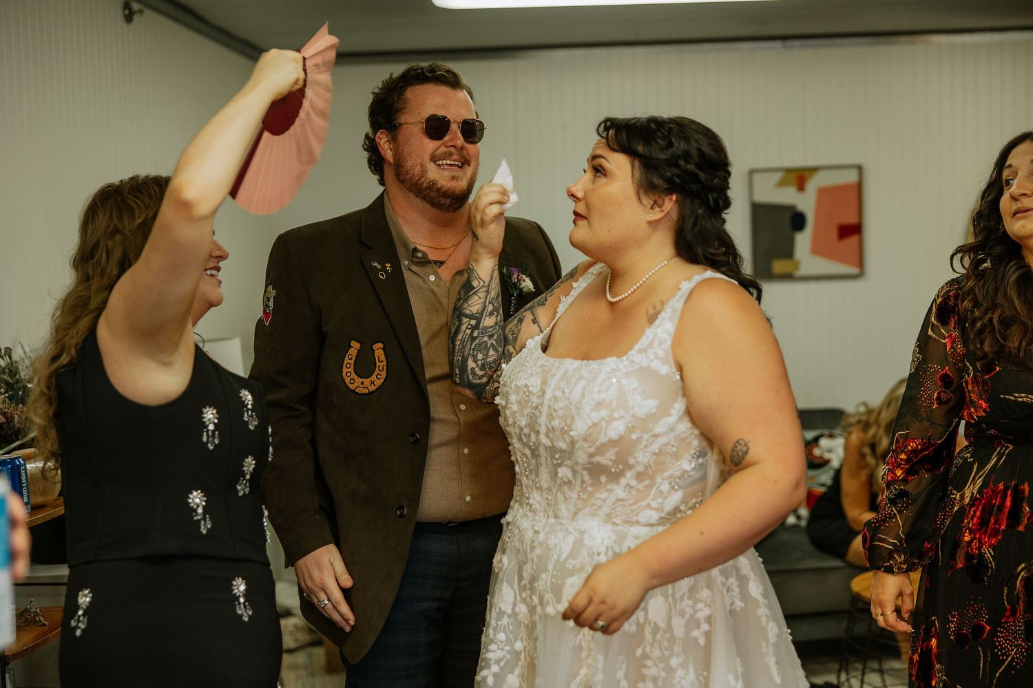 Bride in white lace dress celebrating joyfully with wedding guests before the ceremony.