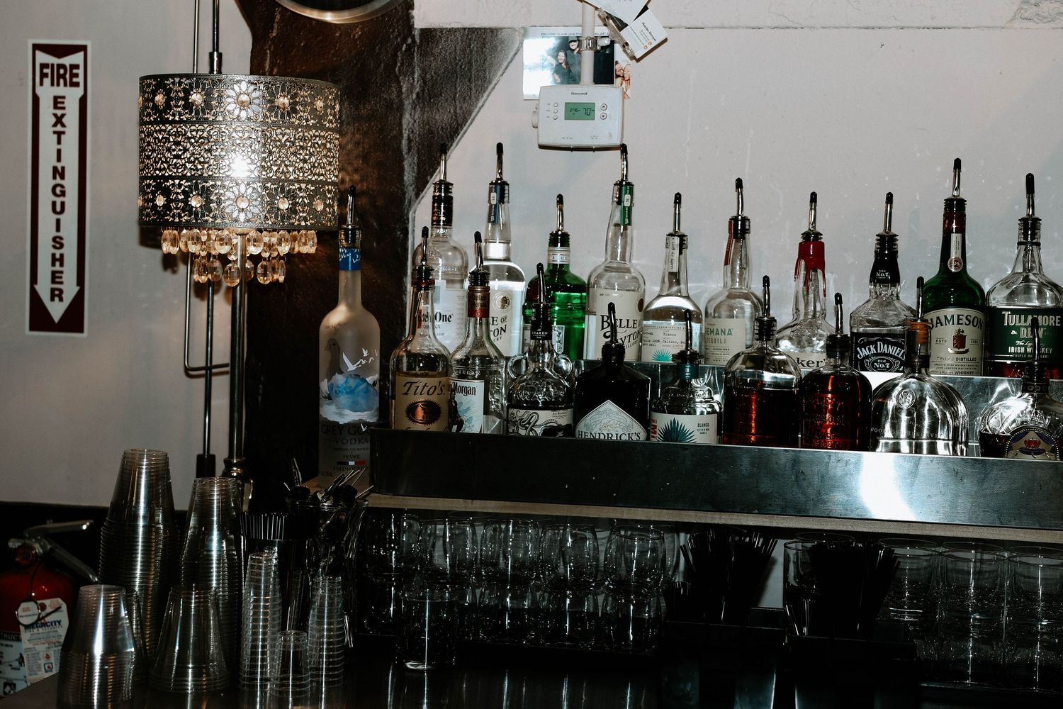 Bar shelf stocked with assorted liquor bottles and glassware at a wedding venue.