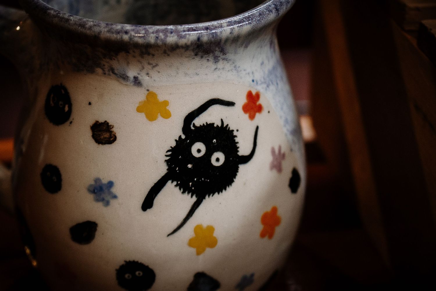 Ceramic mug featuring a cute Soot Sprite from Studio Ghibli with colorful flowers and black polka dots.