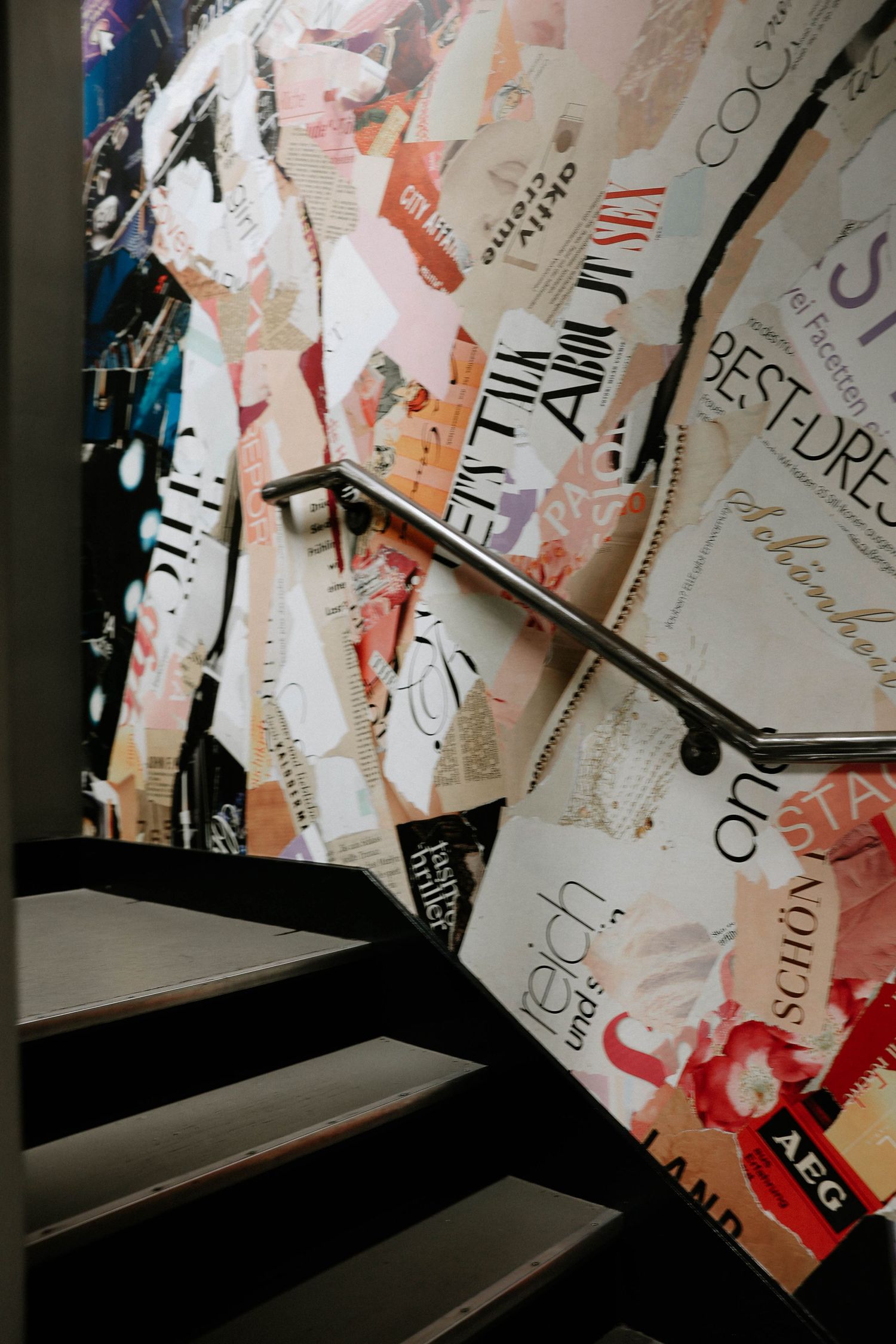 Staircase with collage wall art featuring magazine clippings, text, and colorful paper pieces in a modern interior.
