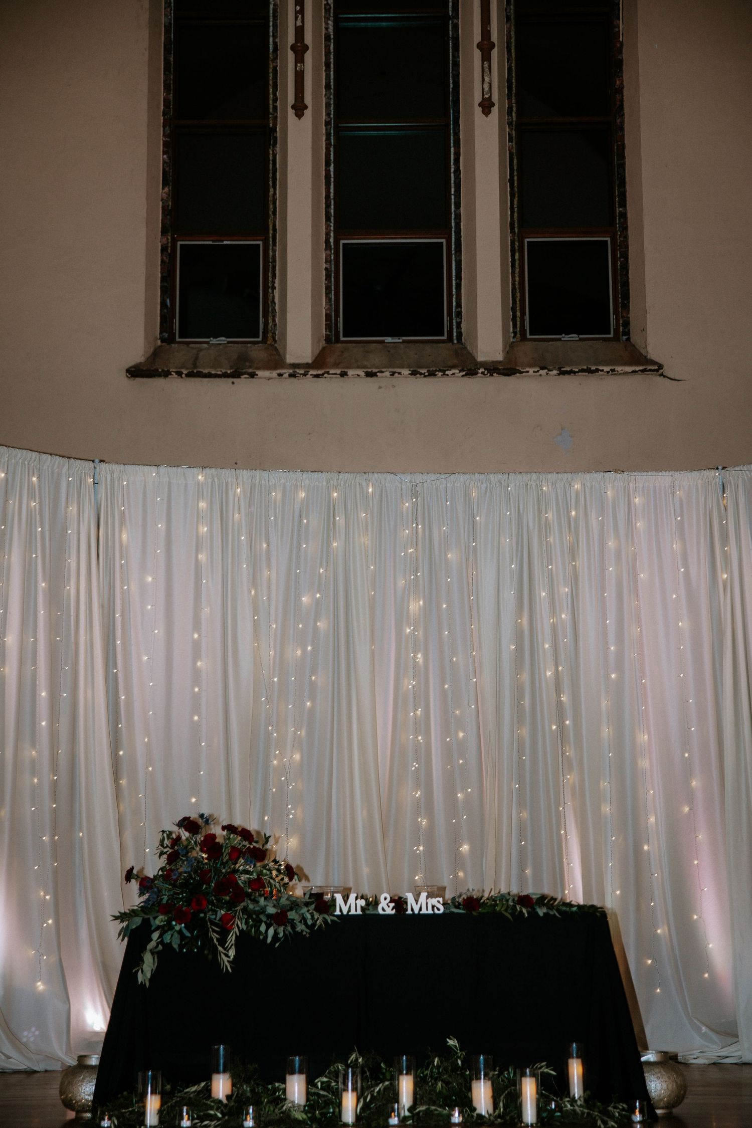 Wedding sweetheart table with Mr and Mrs sign, candles, and twinkling light curtain backdrop at Urban Artifact in Cincinnati, Ohio
