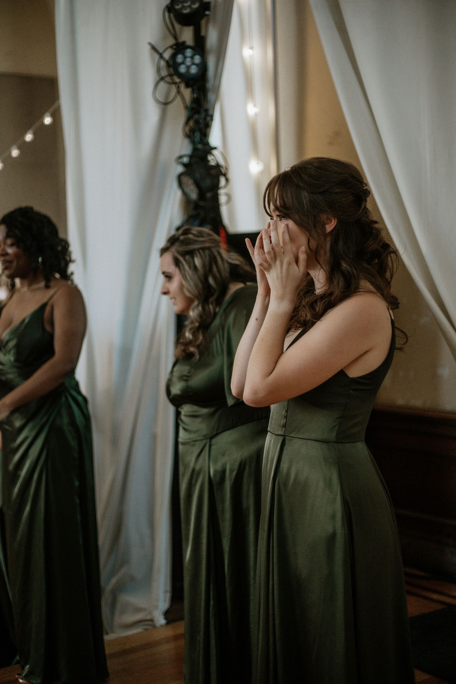 Tearful bridesmaid in olive green satin gown covers her face during an emotional wedding ceremony at Urban Artifact in Cincinnati, Ohio
