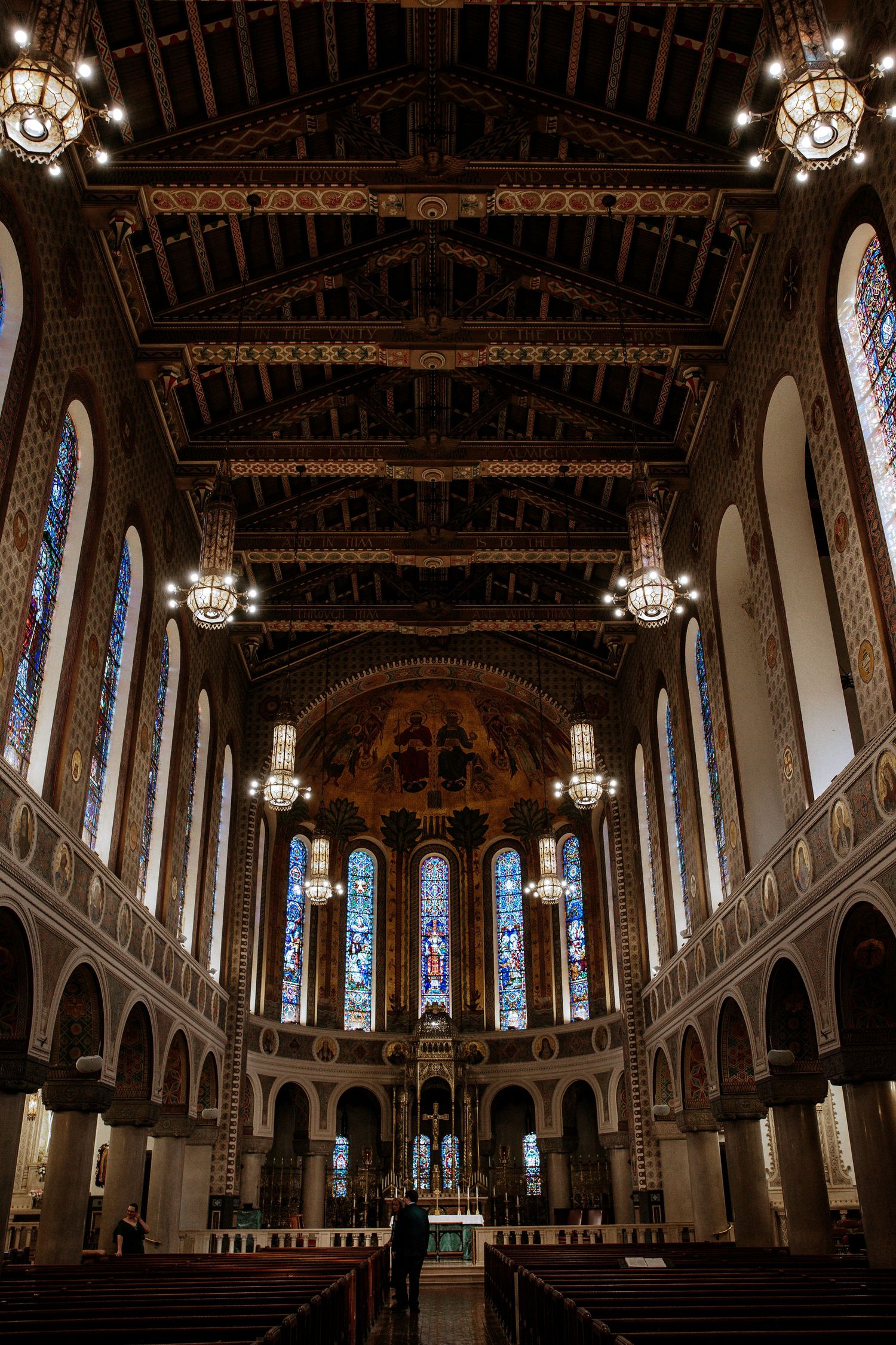 Grand cathedral interior with vaulted wooden ceiling, stained glass windows, chandeliers, and ornate altar in Cincinnati, Ohio