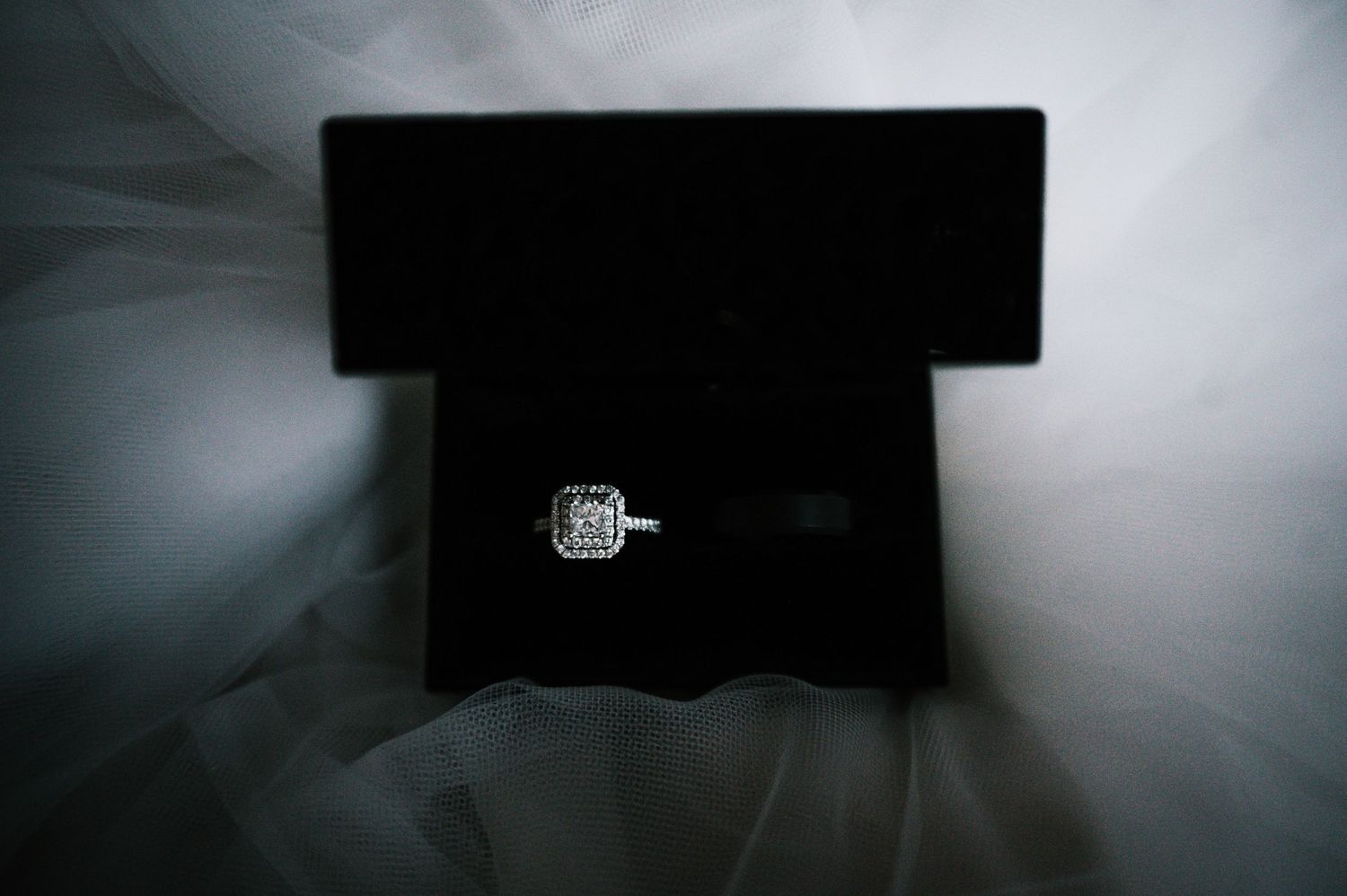 Square halo diamond engagement ring displayed in black velvet jewelry box.