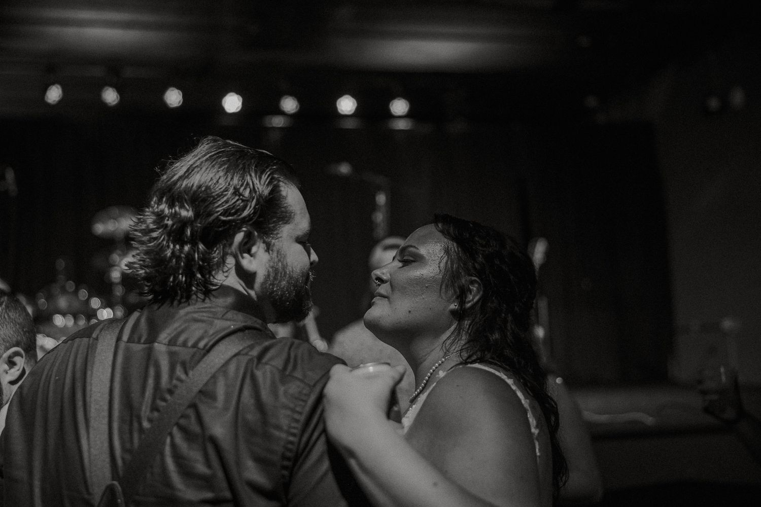 Couple sharing an intimate moment on a dimly lit dance floor in black and white photo.