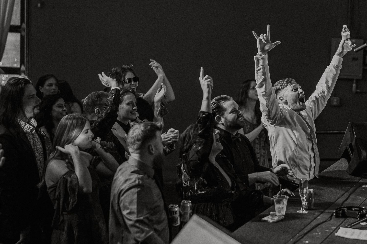 Excited crowd raises hands and makes rock signs at energetic live music event.