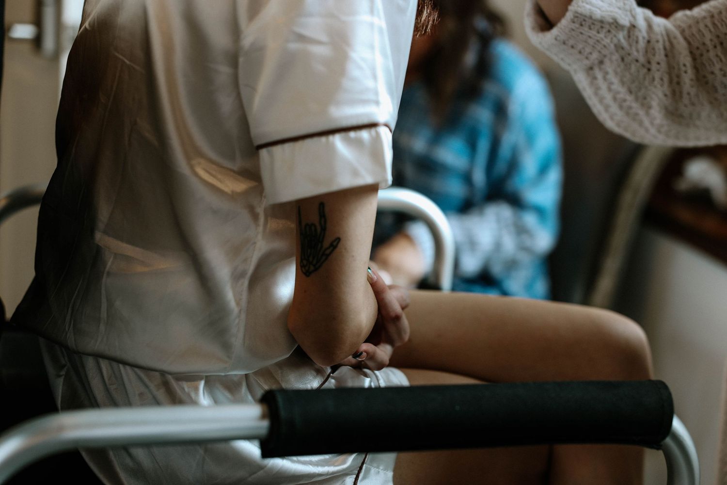 Nurse holding elderly patient's hand near a walker, providing compassionate care and support in a healthcare setting.