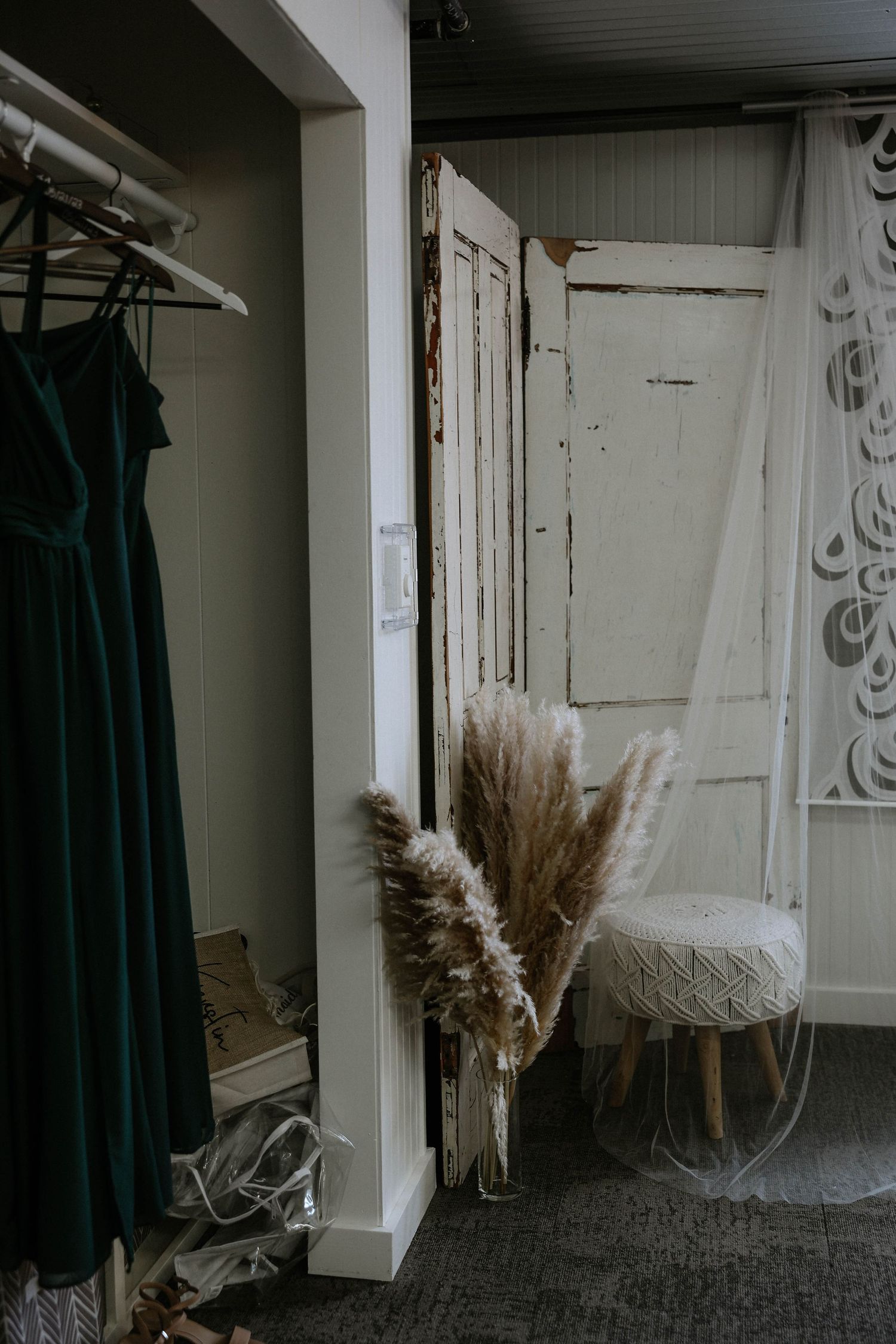 Elegant bridal suite with green velvet dress, pampas grass, vintage doors, and a tufted stool.