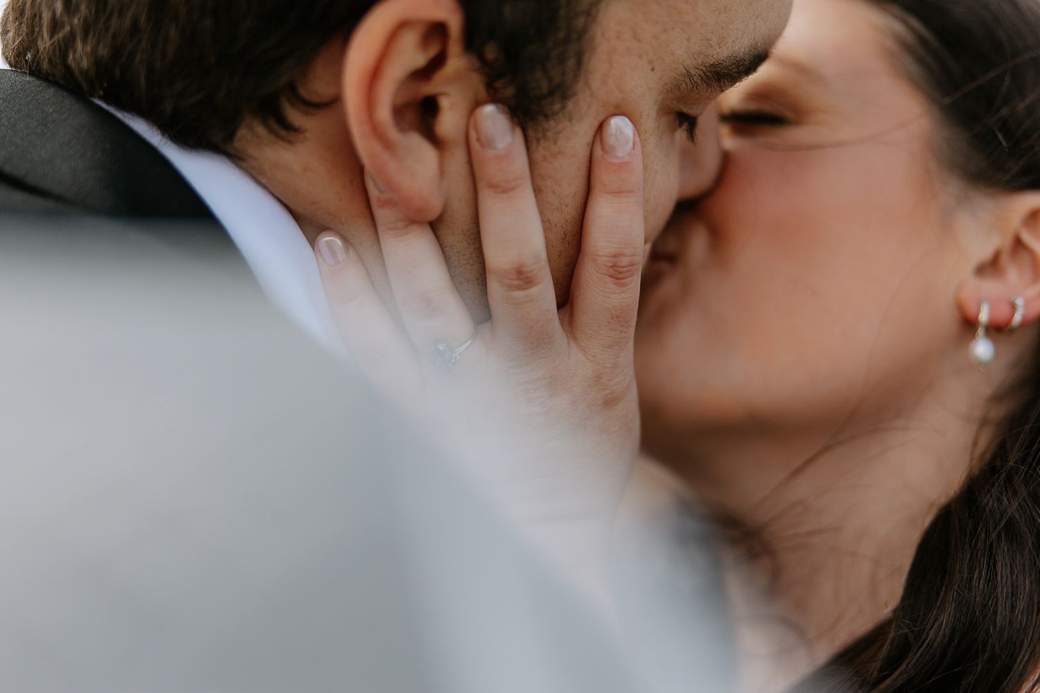 Close-up of bride and groom kissing with her hand gently cradling his face on their wedding day.