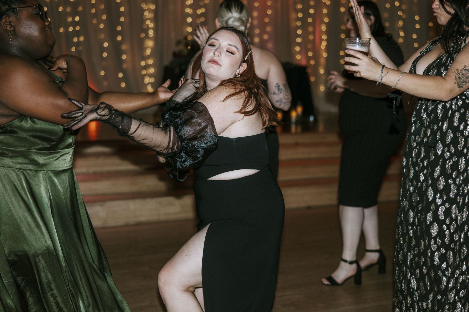 Woman in black dress dancing energetically with guests at wedding reception in Cincinnati, Ohio