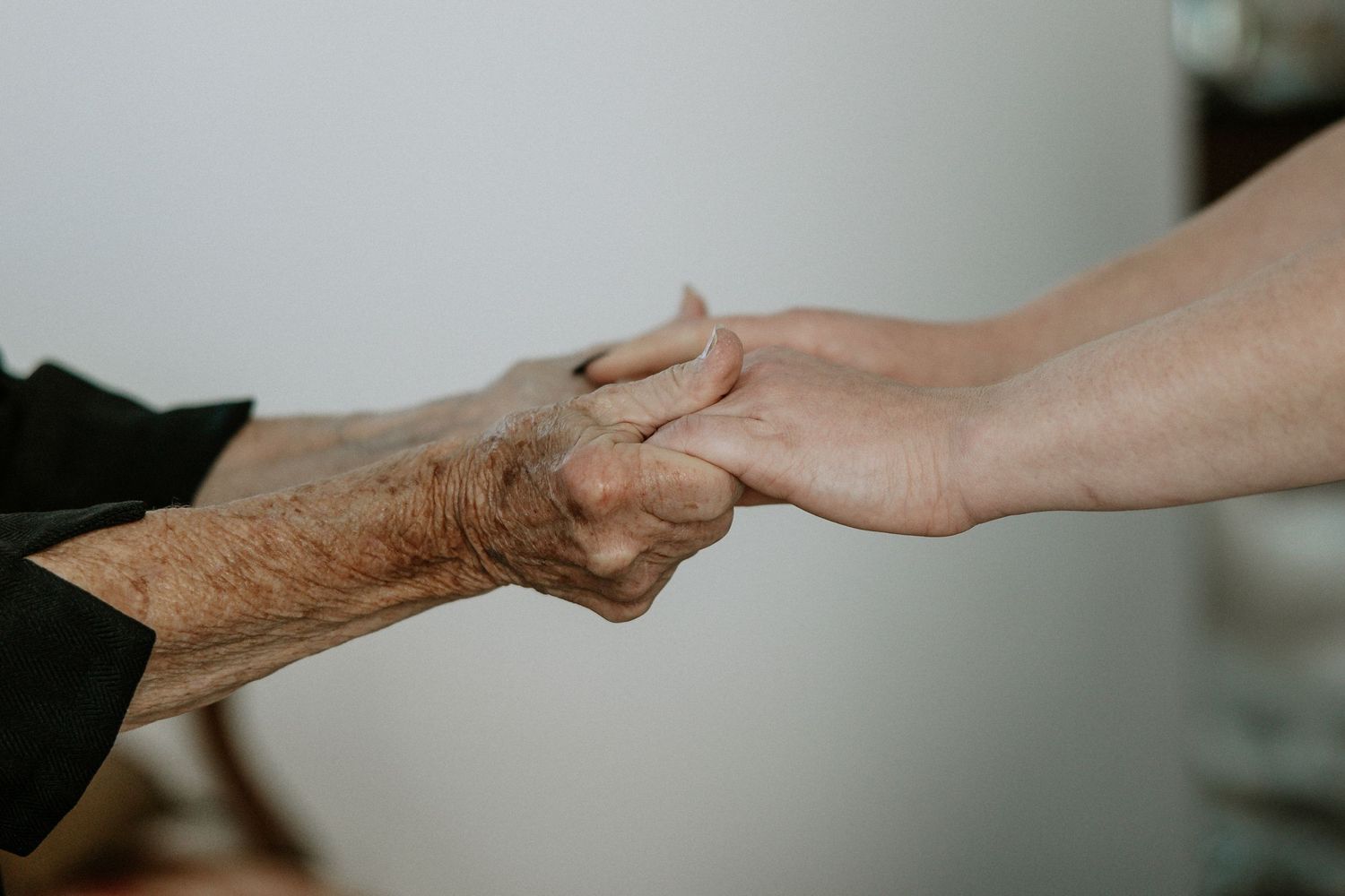 An elderly person and a younger person tenderly holding hands together at Urban Artifact in Cincinnati, Ohio