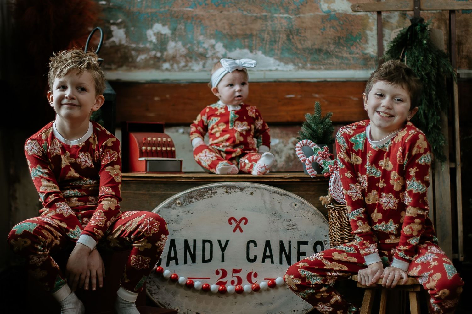 Three children in matching Christmas pajamas posing with candy cane sign in Cincinnati, Ohio.