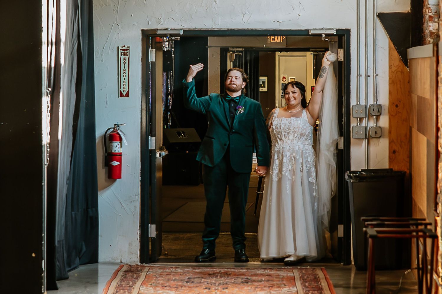 Bride and groom making grand entrance through doorway at wedding reception venue.