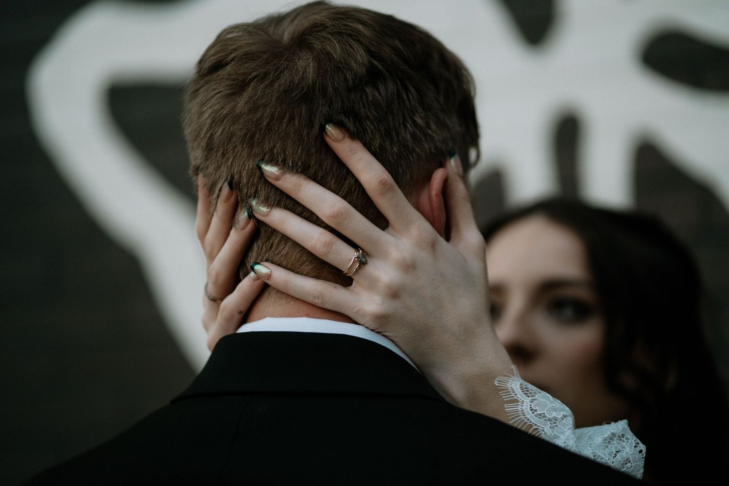 Bride placing her hand on groom's neck showing wedding ring during romantic wedding ceremony moment.