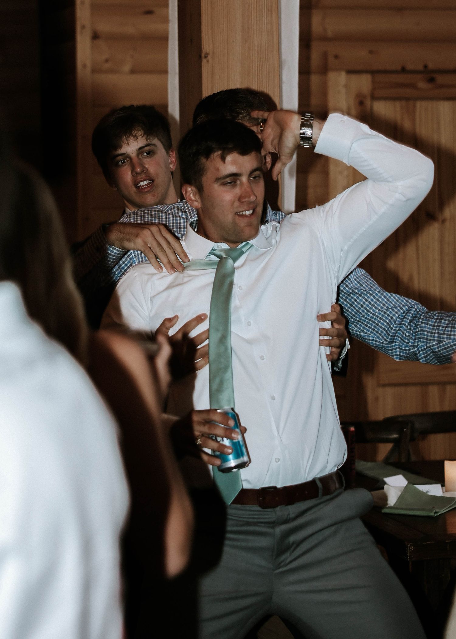 Guests dance and celebrate joyfully inside a rustic wooden barn at a lively wedding reception.