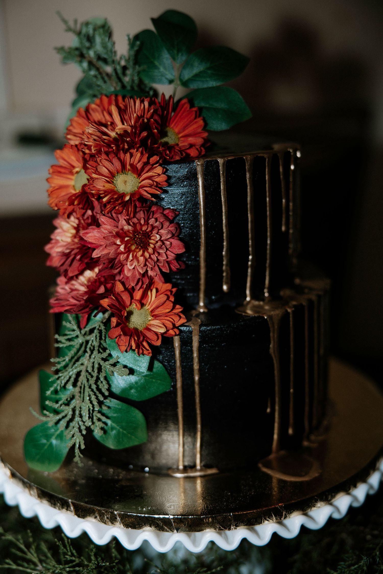 Two-tier black wedding cake decorated with gold drip detail and bold red floral arrangement at Urban Artifact in Cincinnati, Ohio