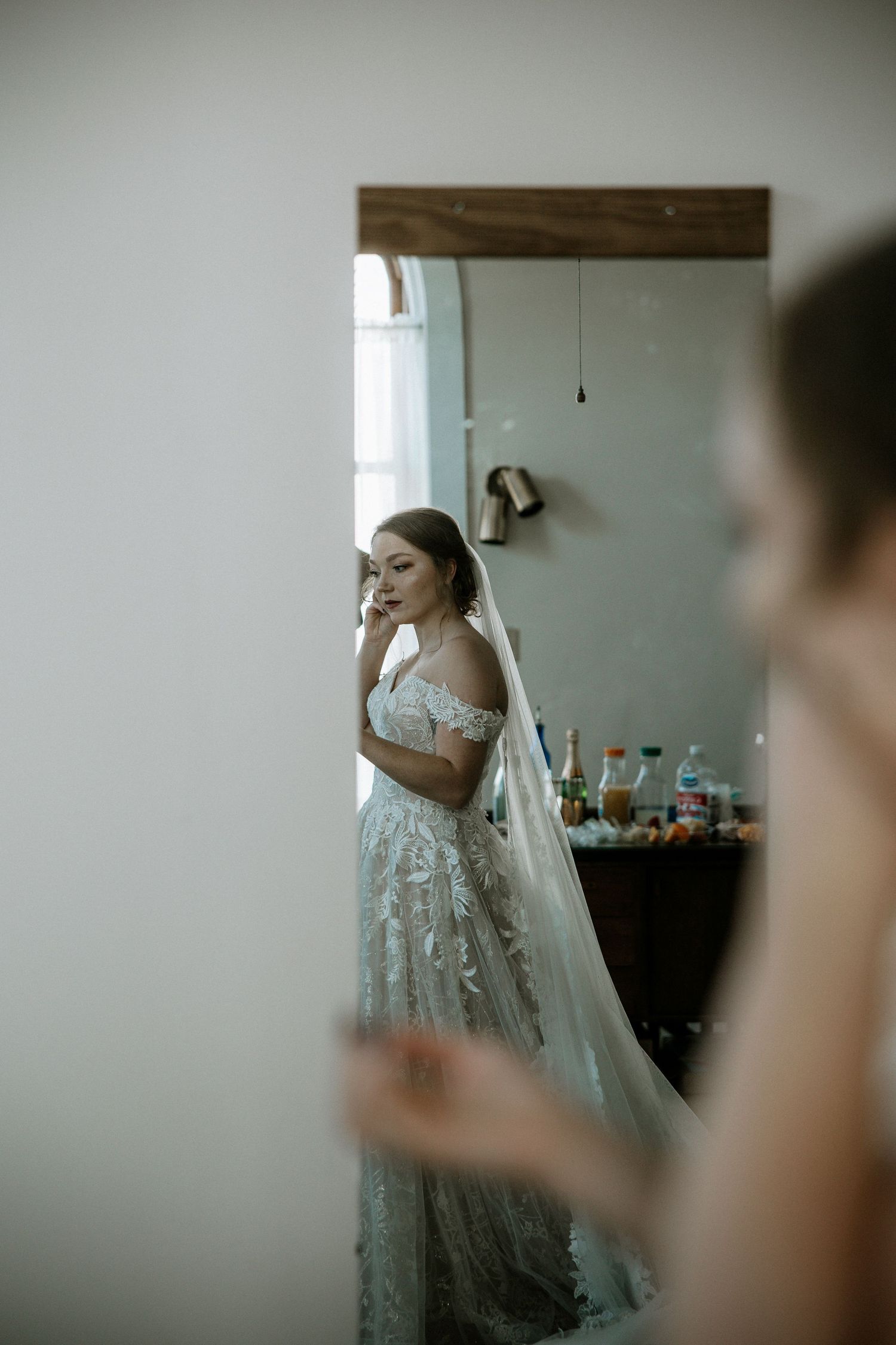 Bride in a flowing lace wedding gown and veil reflected in a full-length mirror during preparations at Urban Artifact in Cincinnati, Ohio