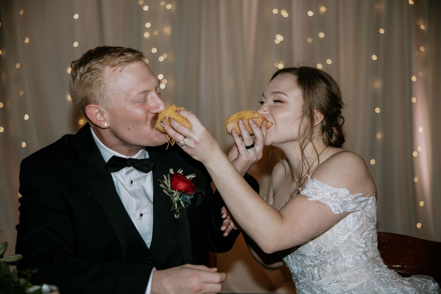 Bride and groom sharing a playful moment eating burgers together at their wedding reception at Urban Artifact in Cincinnati, Ohio