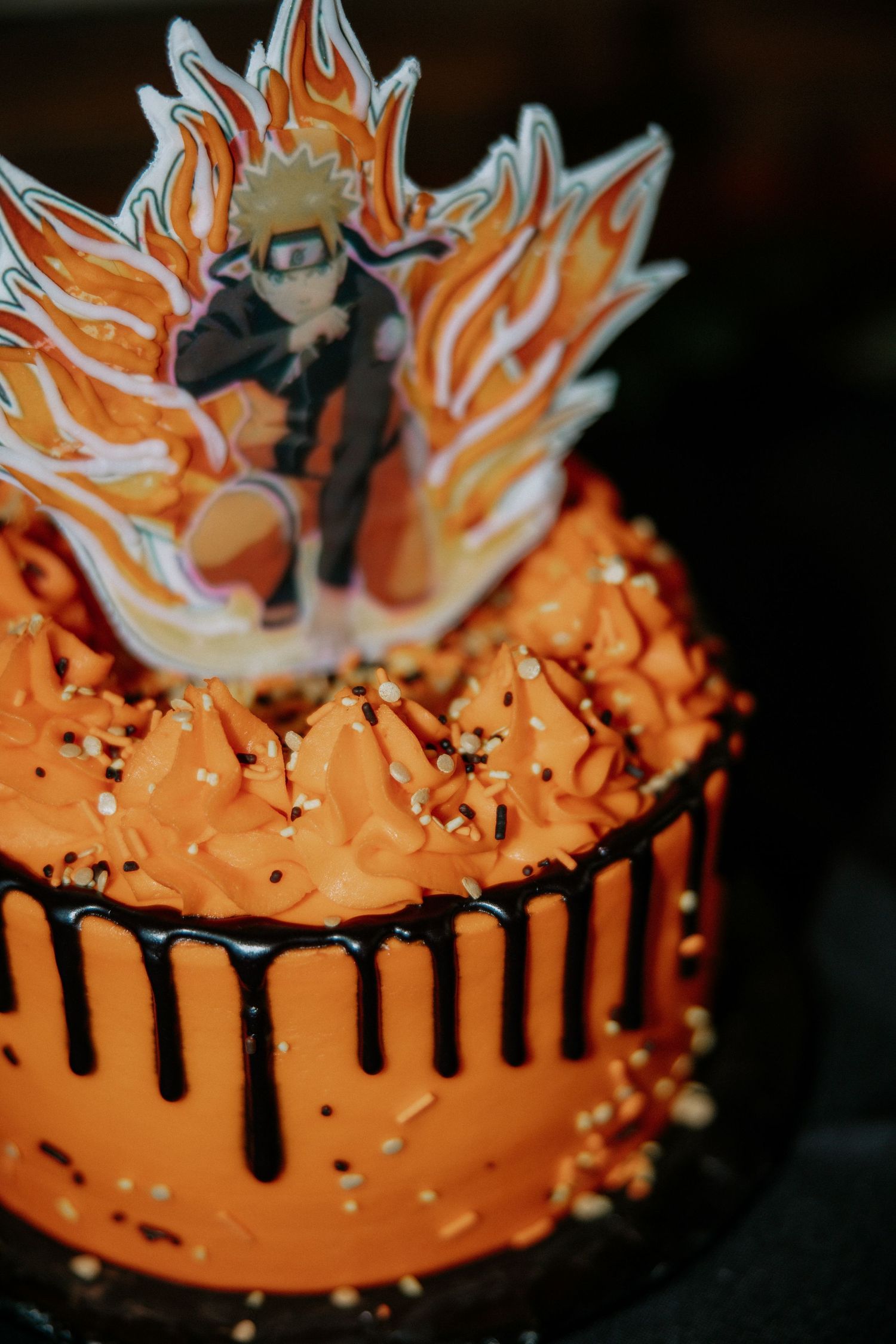 Vibrant orange Naruto anime-themed birthday cake with black chocolate drip and character topper at Urban Artifact in Cincinnati, Ohio