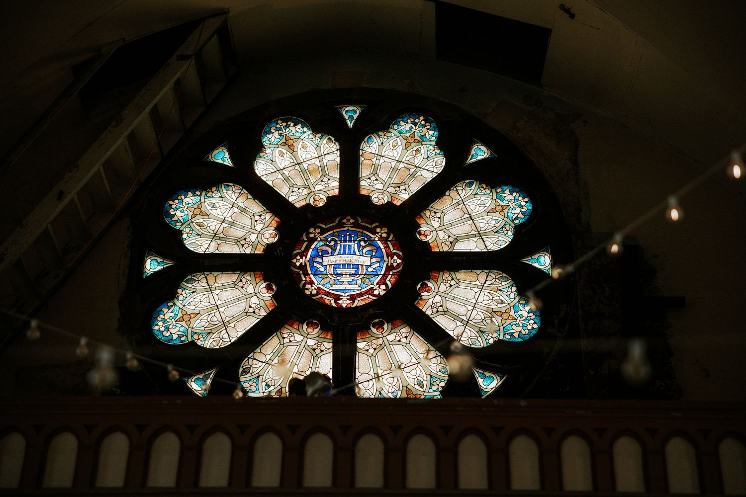 Ornate rose window with colorful stained glass in a historic church illuminated by warm interior light at Urban Artifact in Cincinnati, Ohio