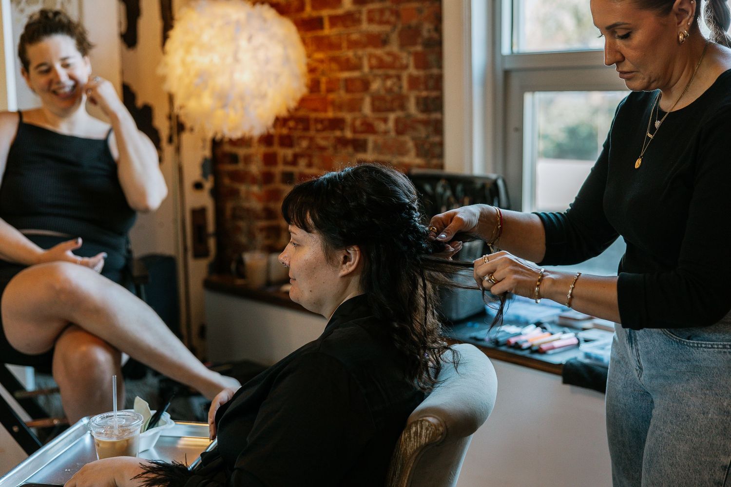Woman getting her hair styled at a salon with brick wall background.