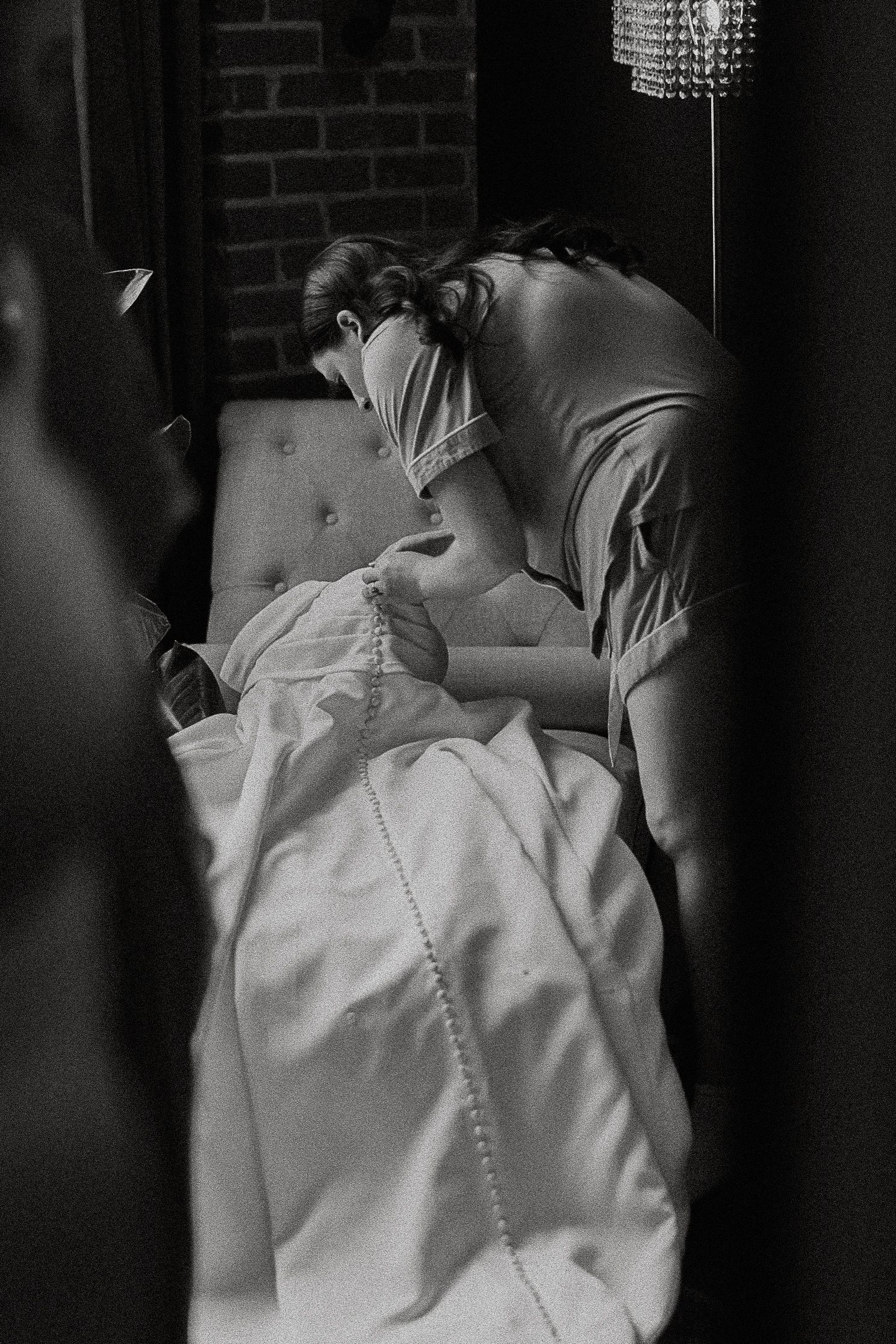 Black and white photo of bride getting helped into her white wedding gown.