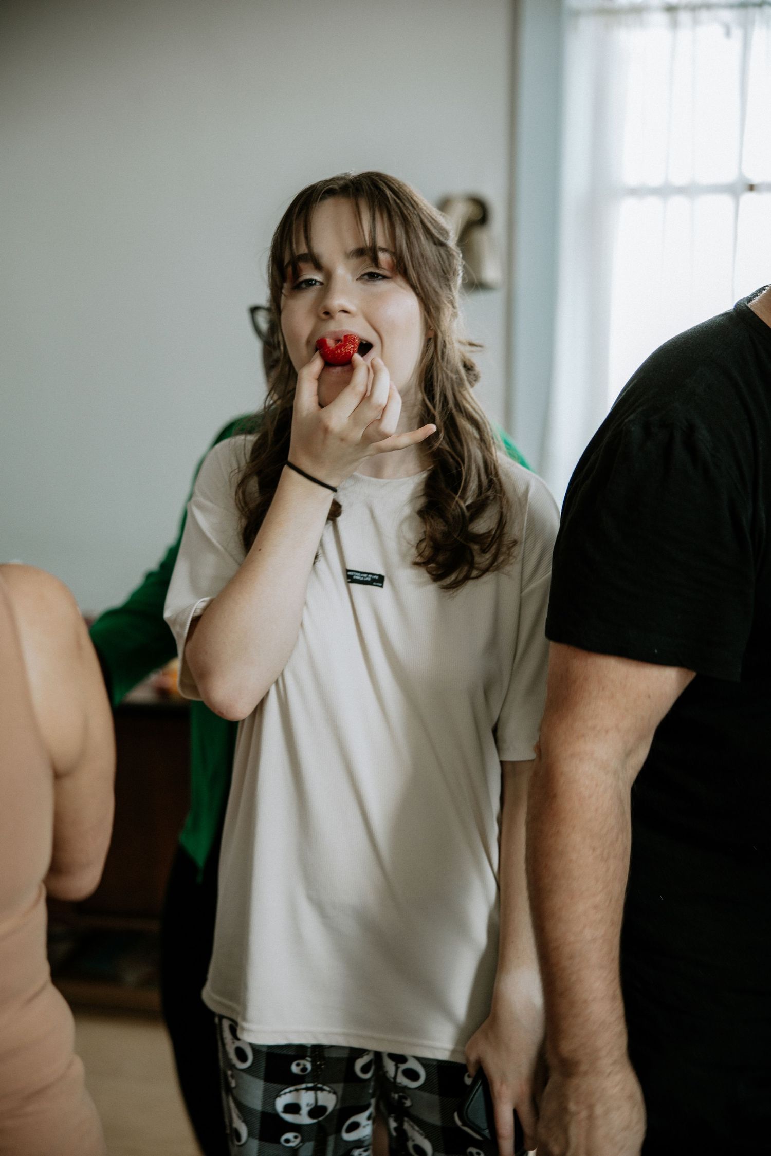 Young bridesmaid eating a strawberry while getting ready for a wedding celebration at Urban Artifact in Cincinnati, Ohio